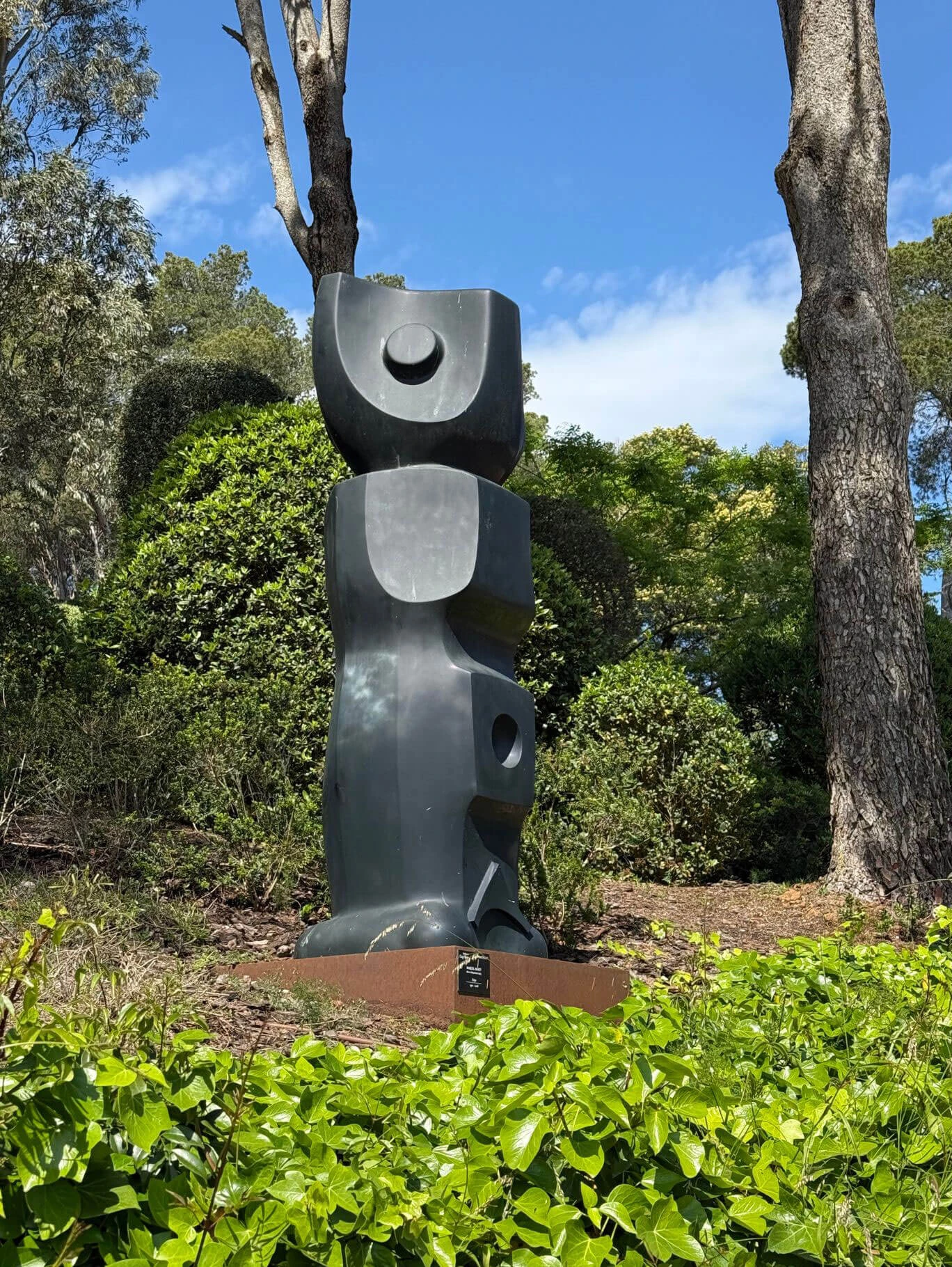Stacked abstract dark sculpture among trees