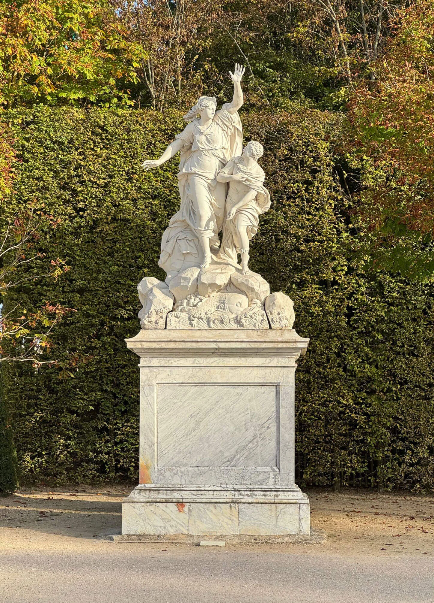 Classical white stone figures on a garden pedestal