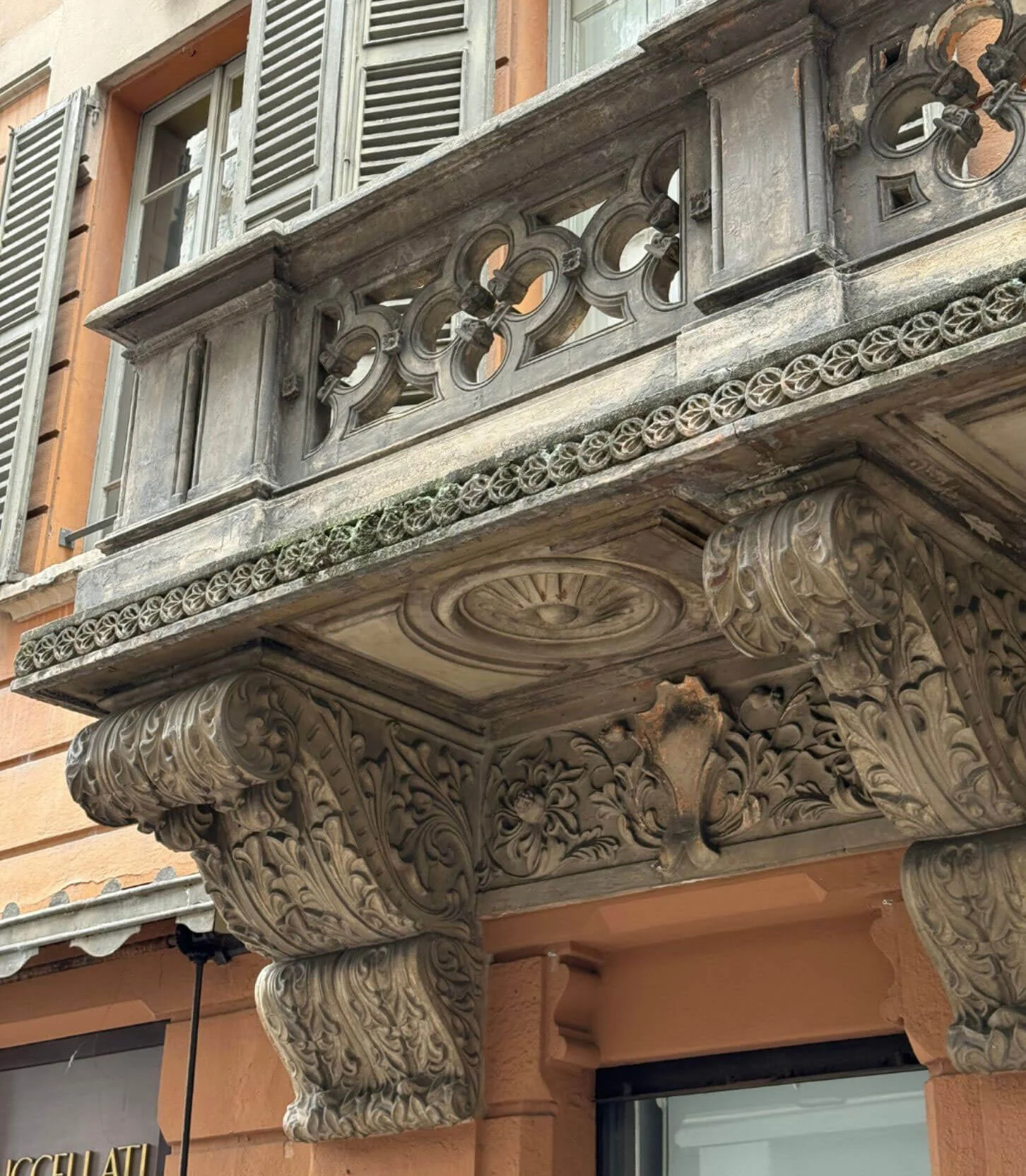 Carved stone figures supporting a balcony beneath shutters