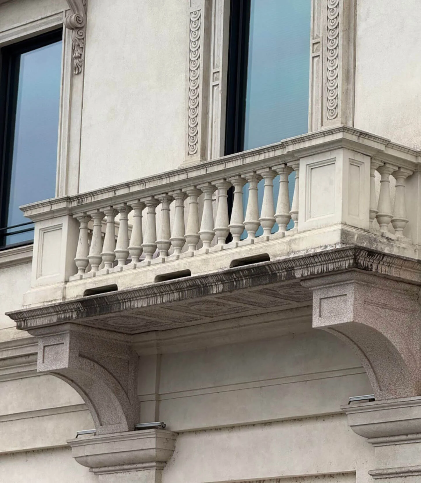 Pale stone balcony with a balustrade and curved supports