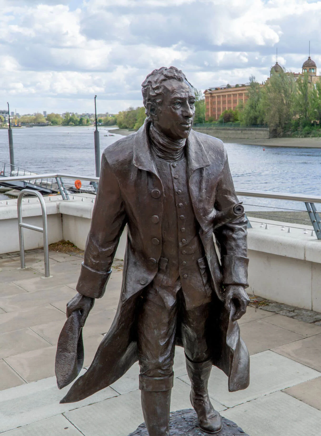 Bronze standing figure beside a waterfront