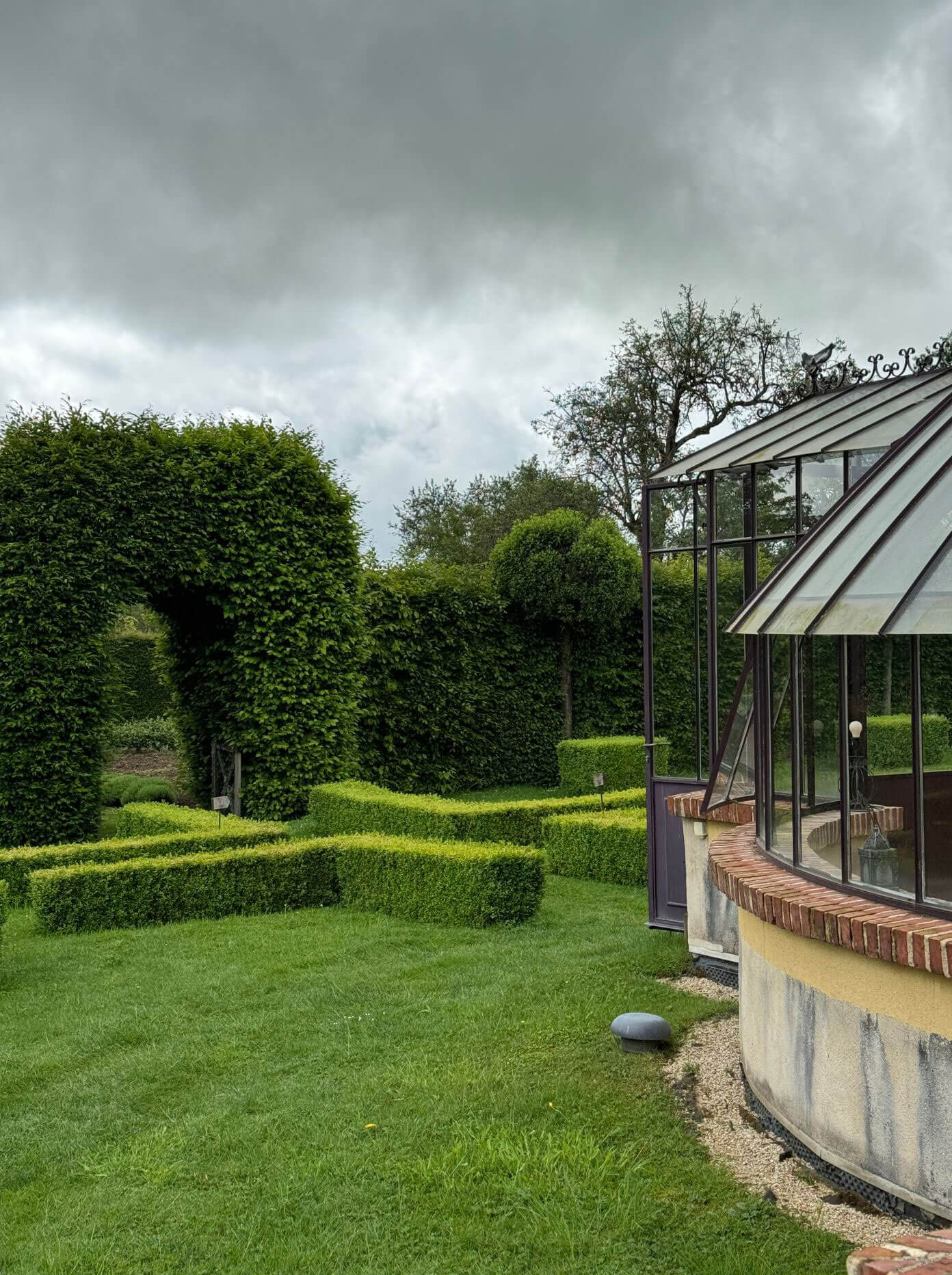 Clipped garden hedges and topiary beside a conservatory