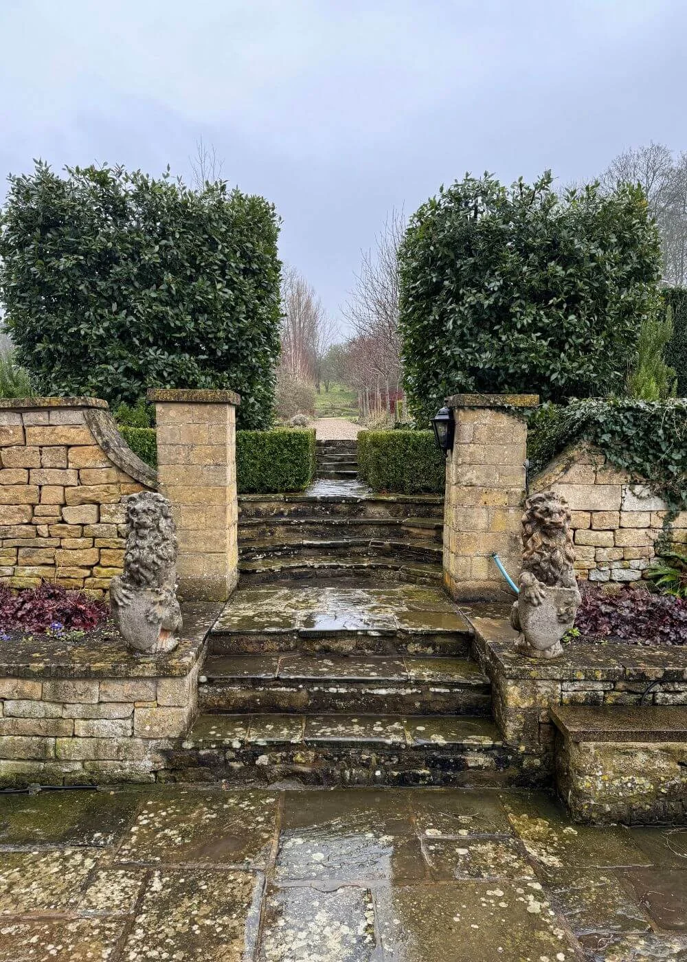 Stone garden steps between low walls and clipped hedges