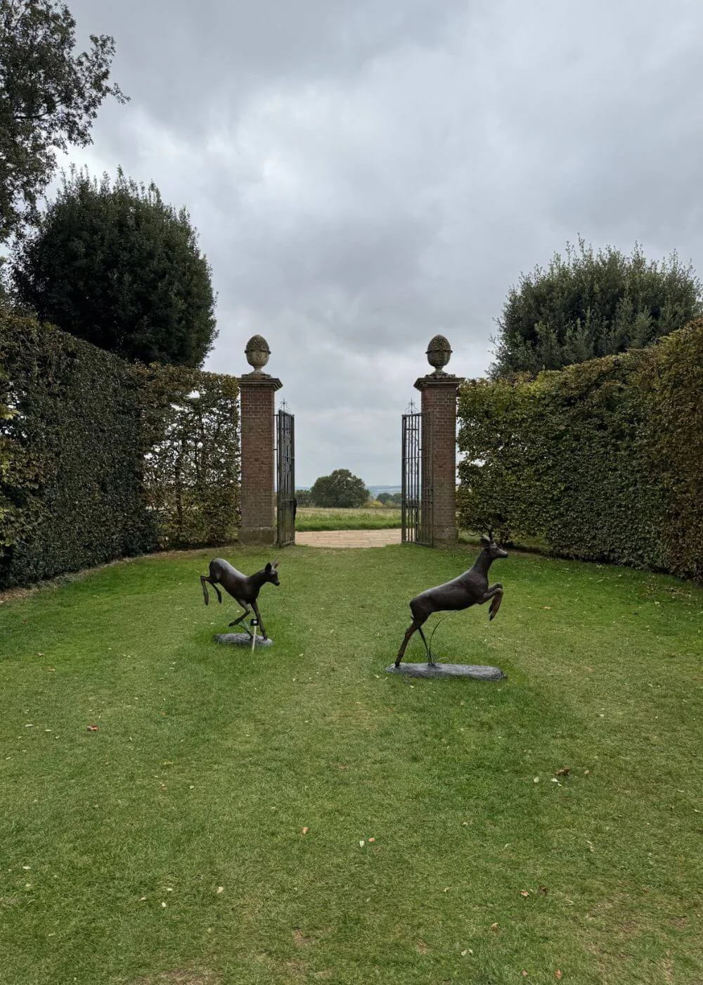Lawn with animal sculptures leading to stone gate pillars