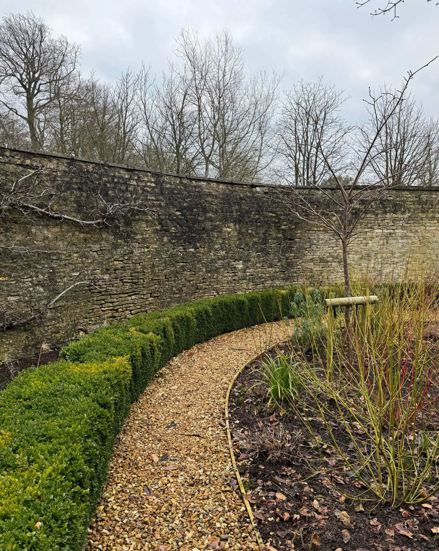 Curved gravel path beside a tall stone wall