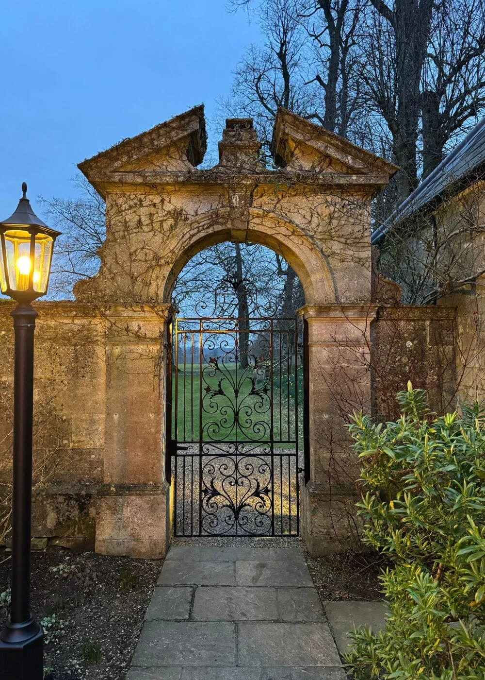 Ornate arched stone gateway lit by a lantern