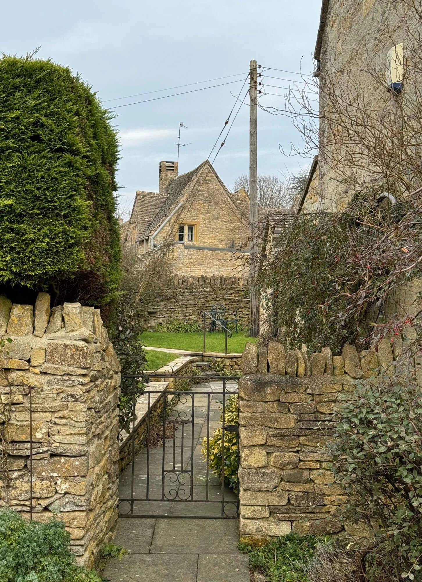 Iron gate between stone walls framing a village house