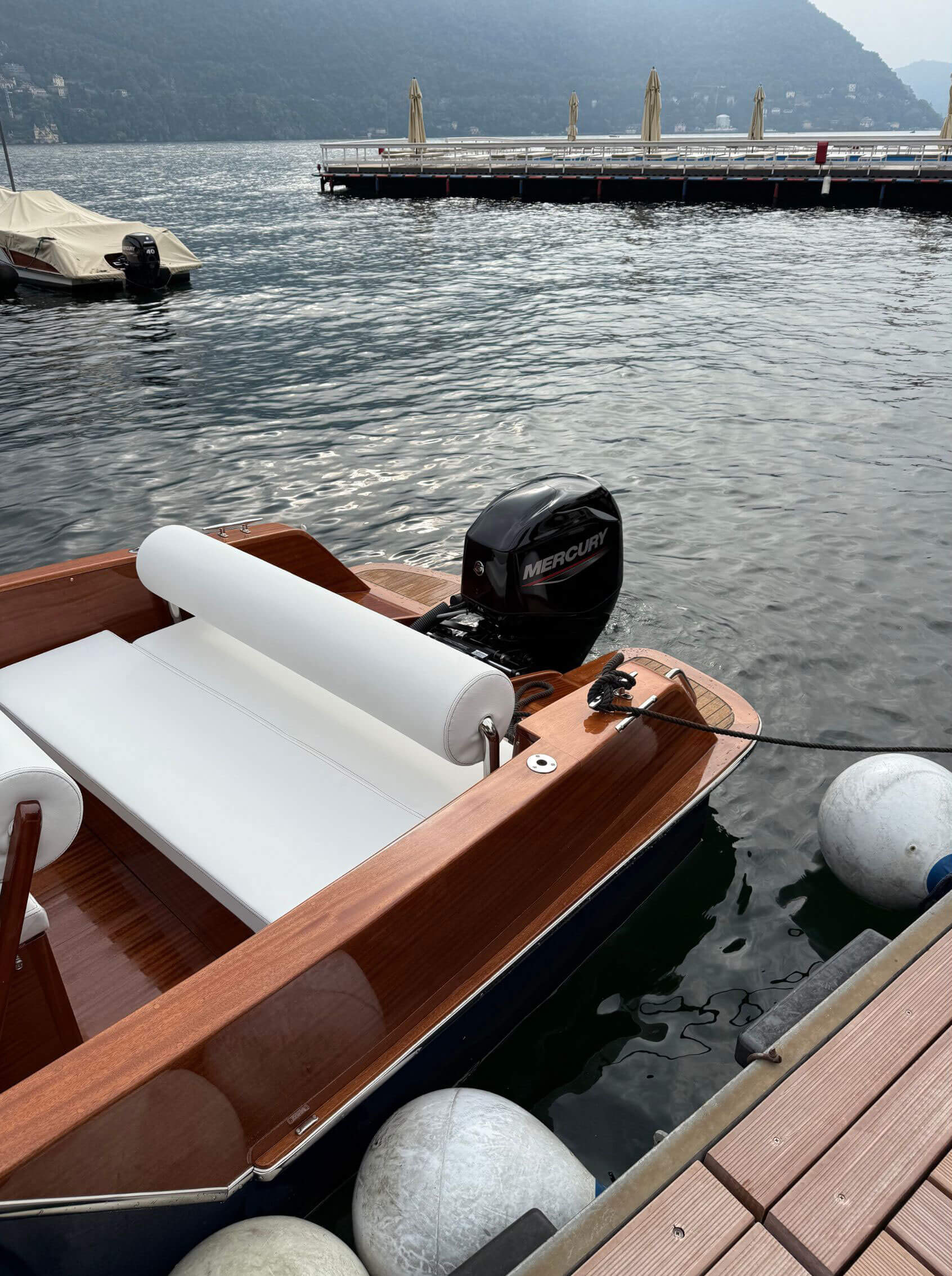 Varnished wooden stern and white seats beside a quay