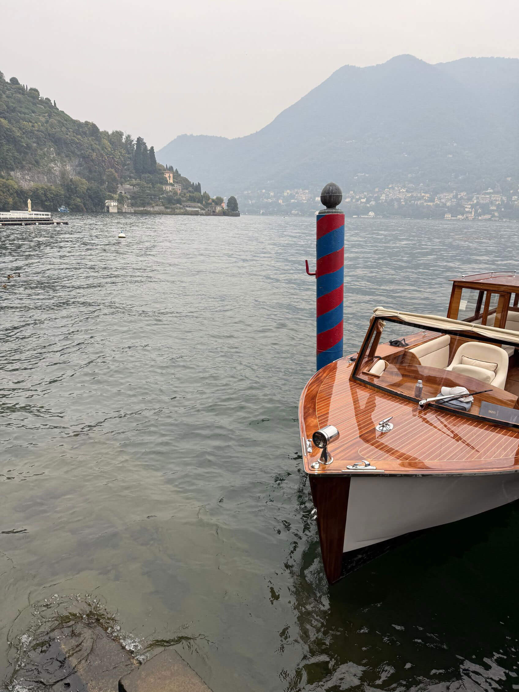 Varnished wooden boat beside a striped mooring post