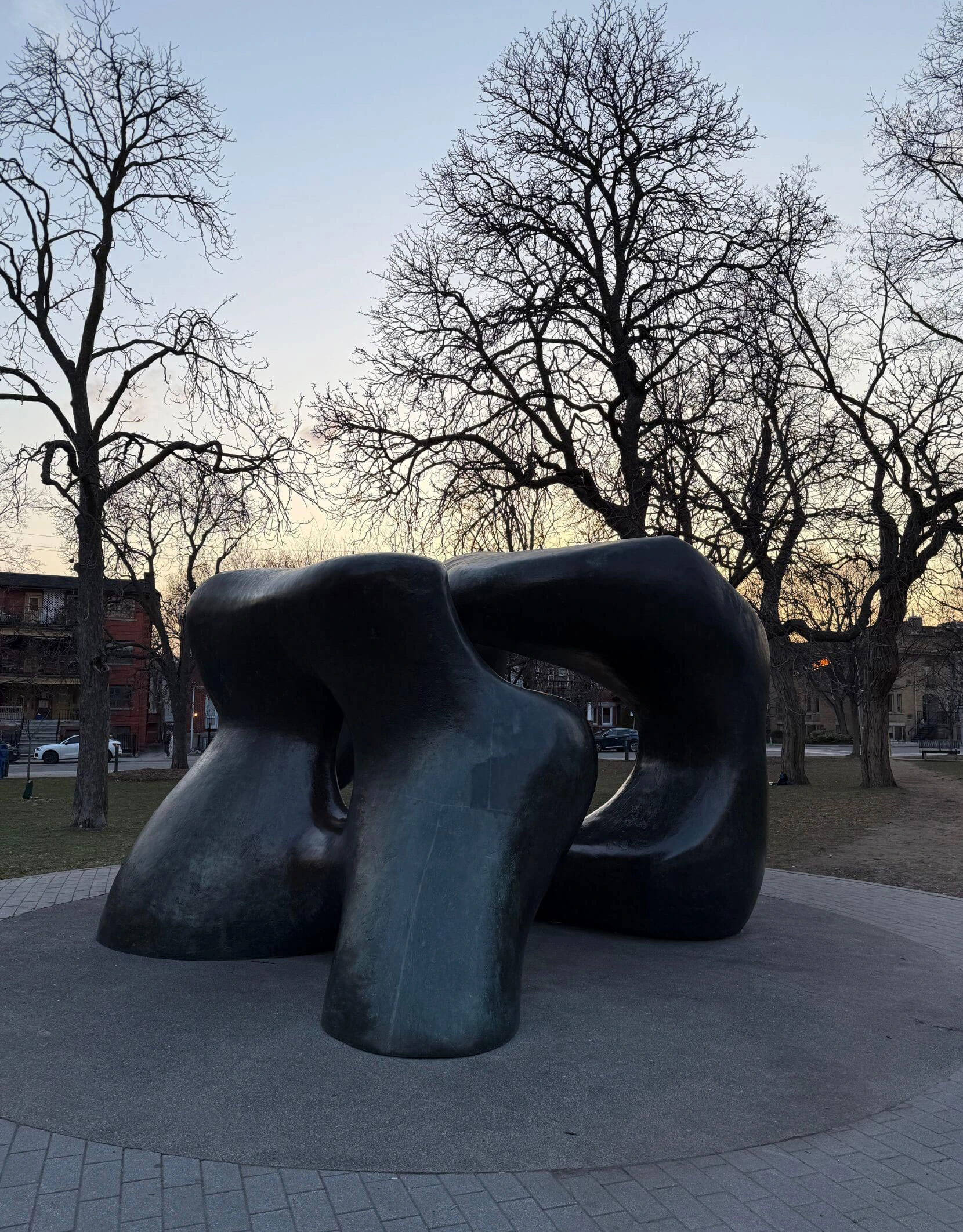 Large bronze sculpture beneath bare trees in a public park