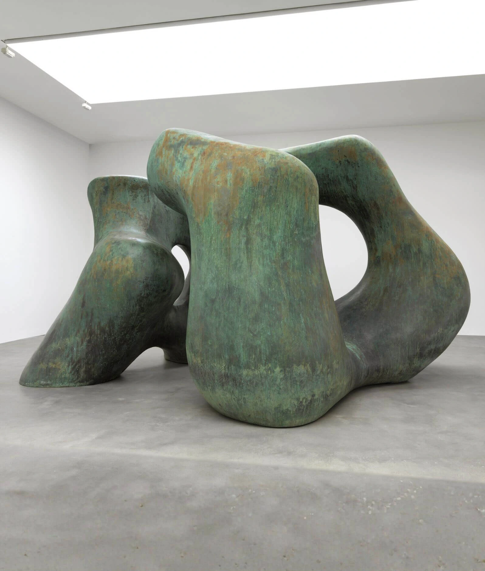 Green-patinated abstract bronze form in a bright gallery