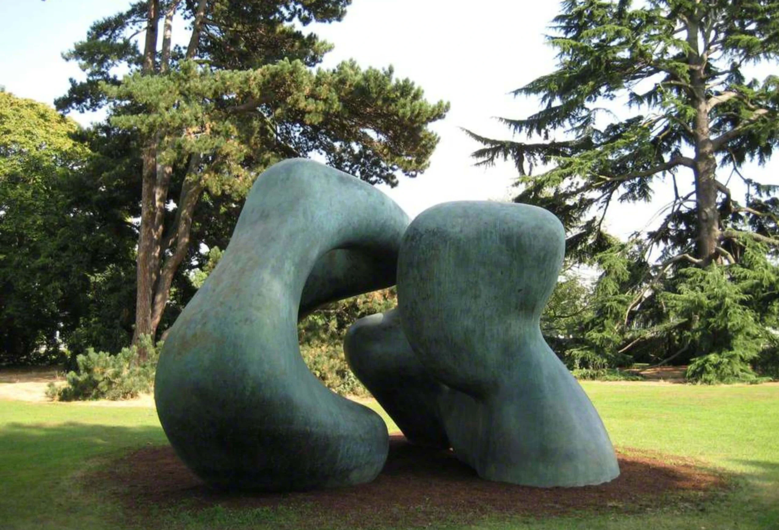 Two rounded bronze forms on a garden lawn