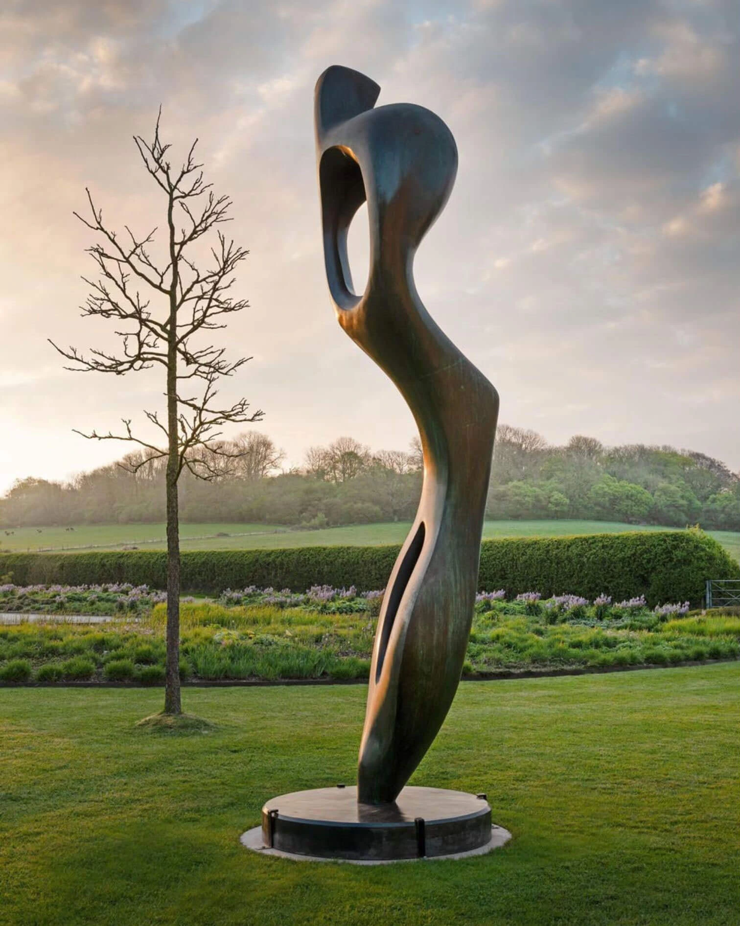 Tall pierced bronze sculpture overlooking open parkland