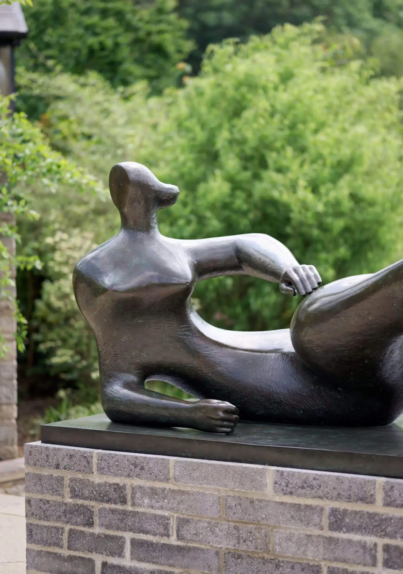 Reclining bronze figure on a low brick plinth