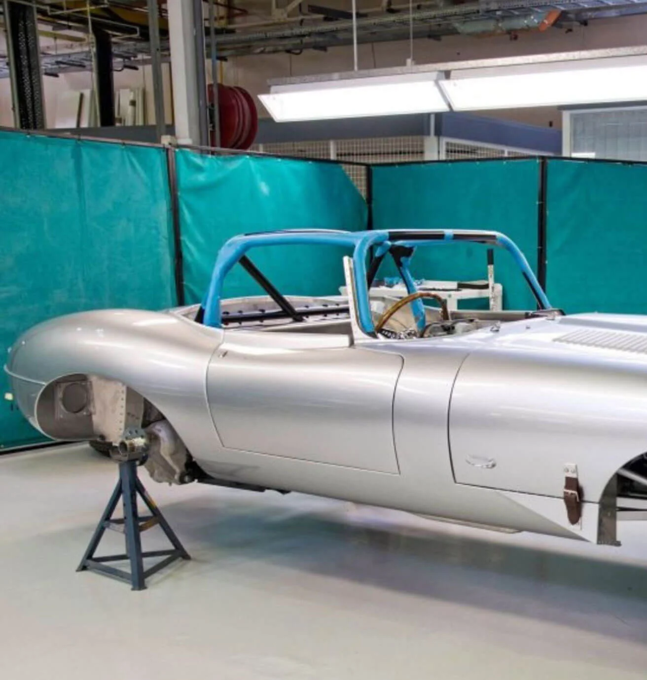Unfinished silver sports car body in a workshop
