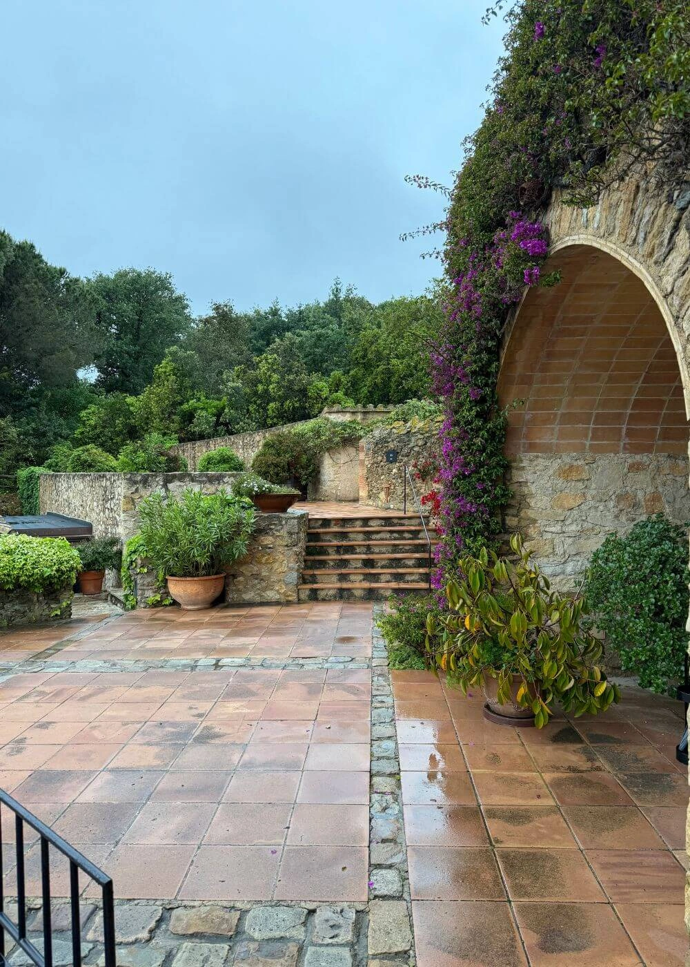Terracotta courtyard paving beside an arched stone passage
