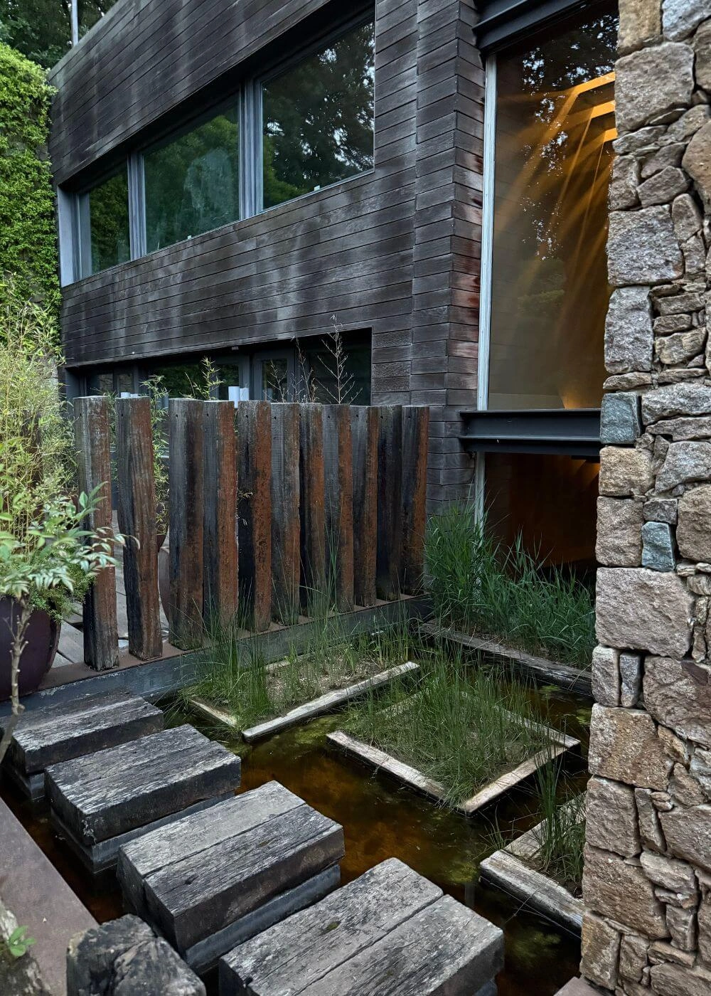 Stepping stones crossing a water feature beside stone and timber walls