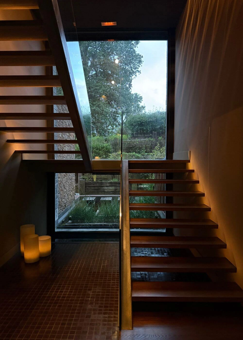 Open timber staircase beside a tall garden window