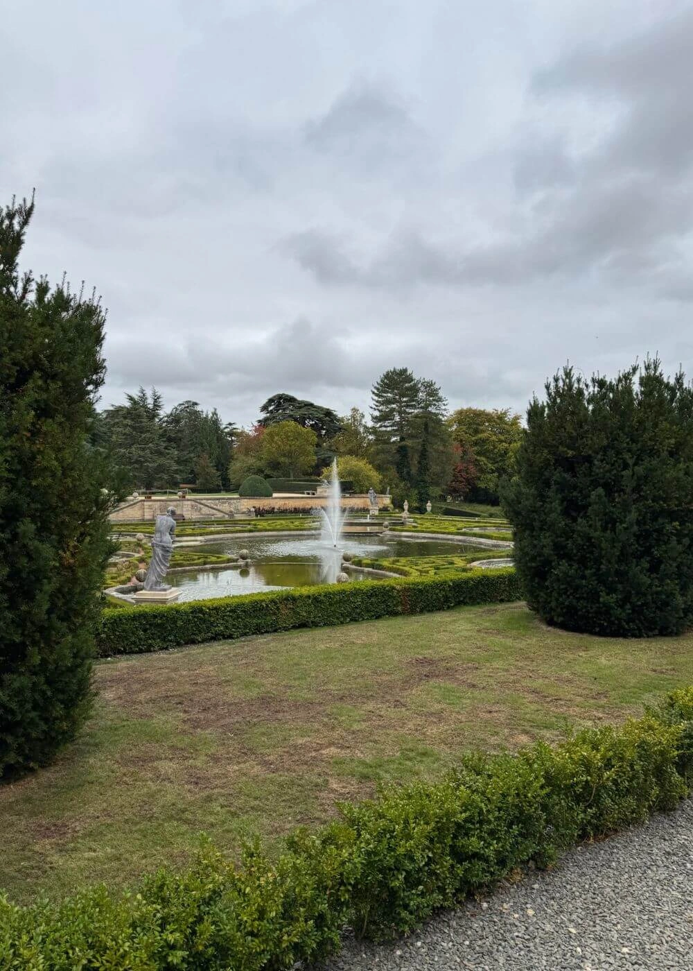 Fountain beyond clipped garden hedges