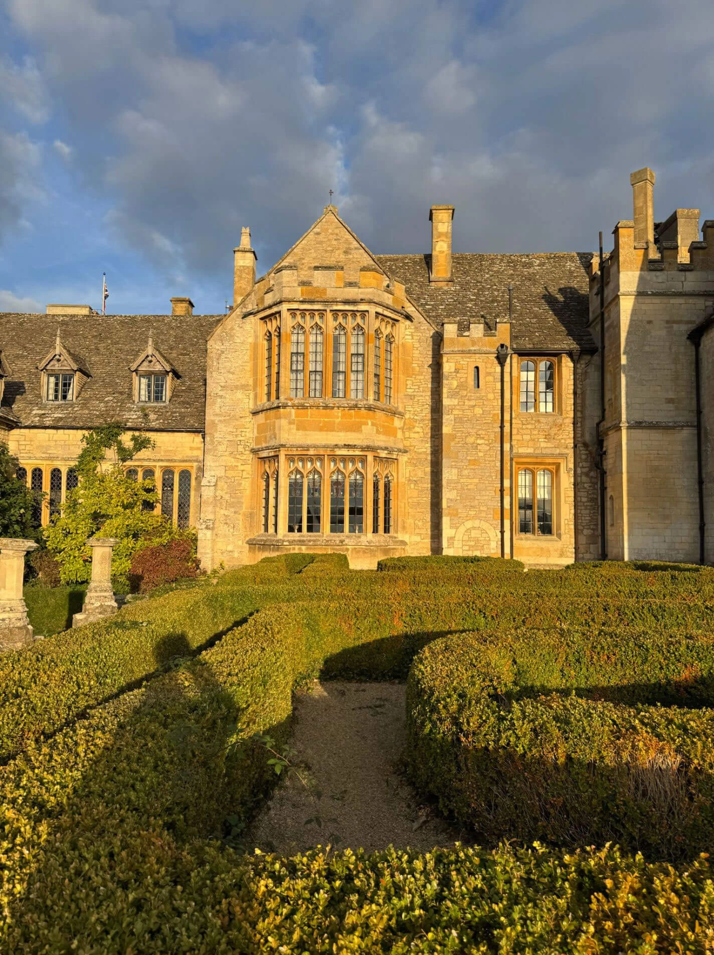 Sunlit manor facade behind geometric hedges