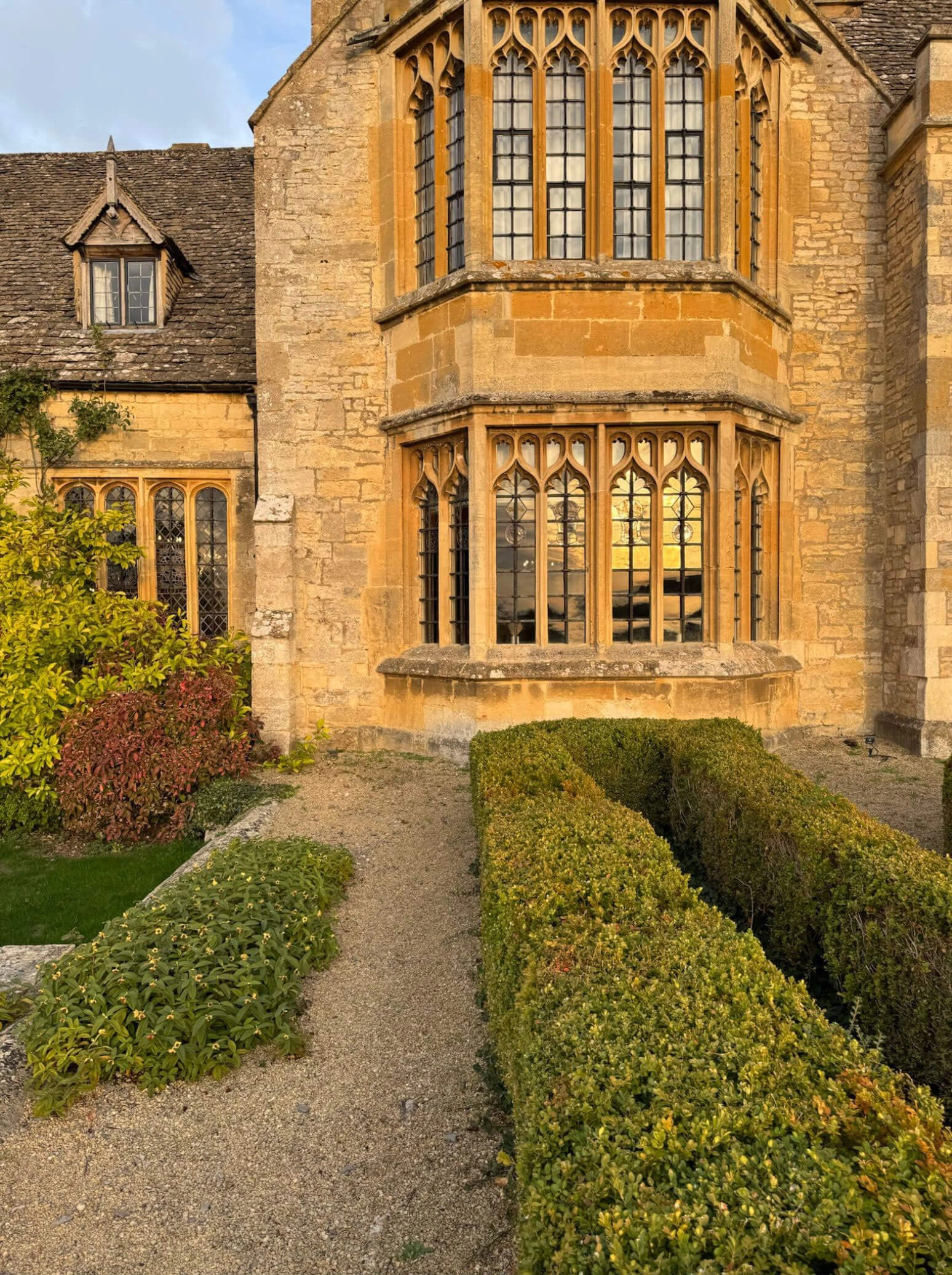 Gravel path leading to a tall stone bay window
