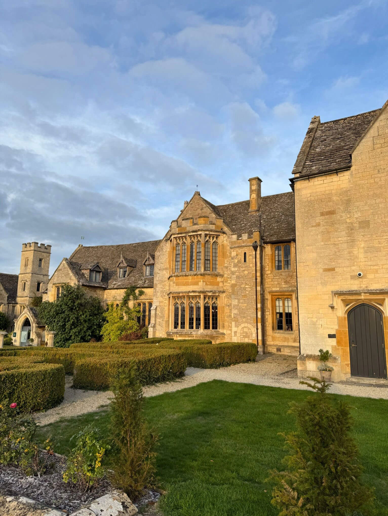 Stone garden walls and hedges before the manor facade