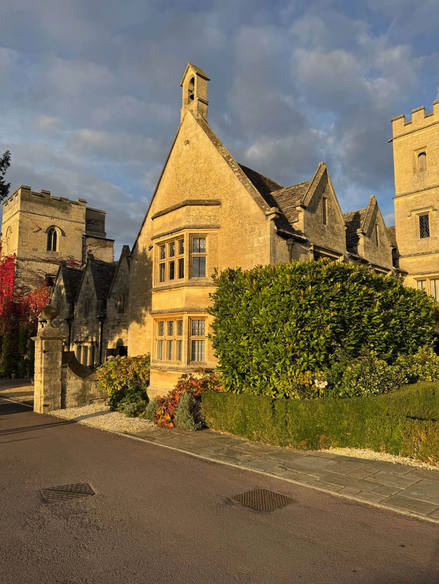Golden stone gables and climbing plants beside a drive