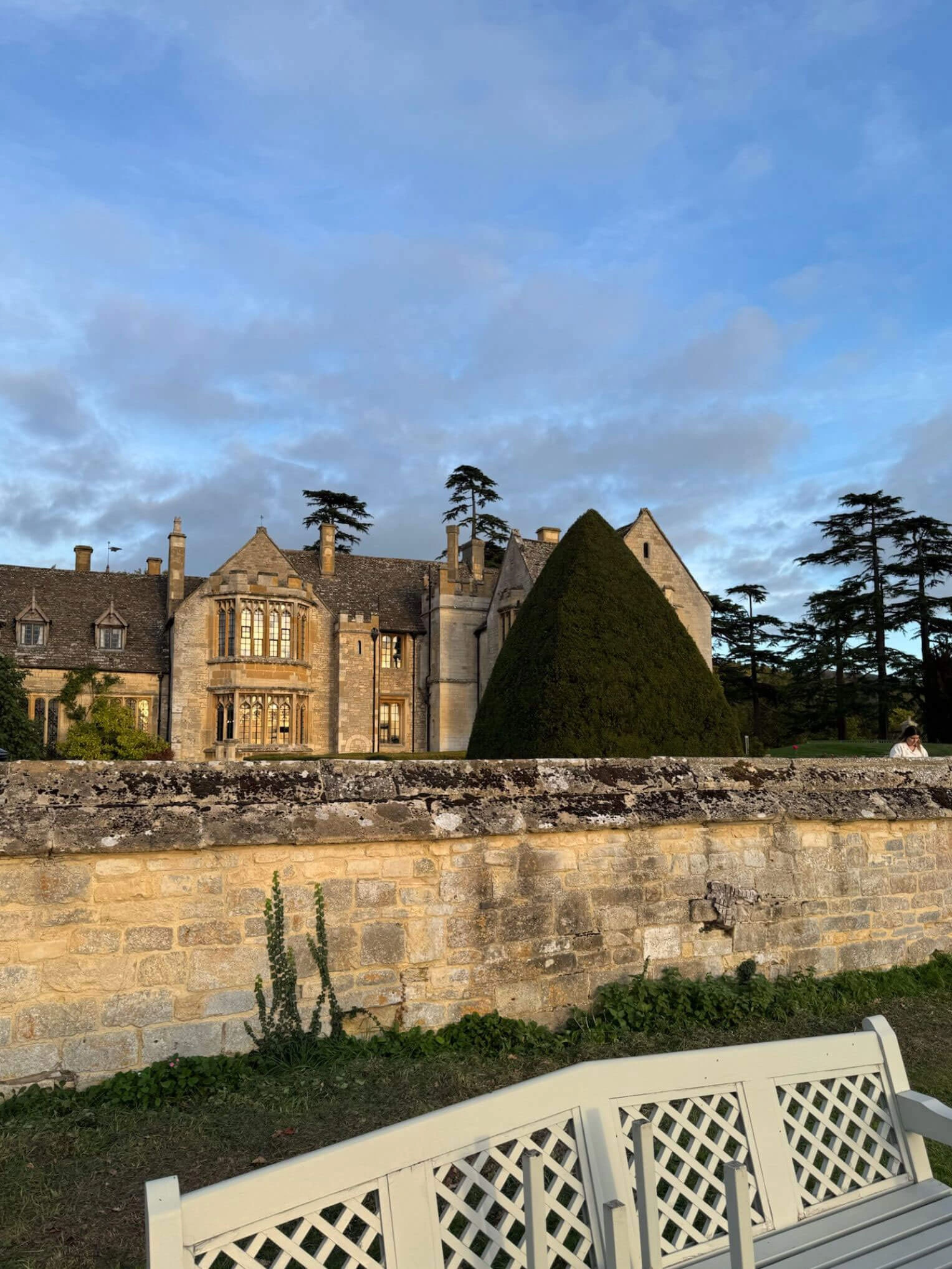 Manor roofs and turrets above a stone garden wall