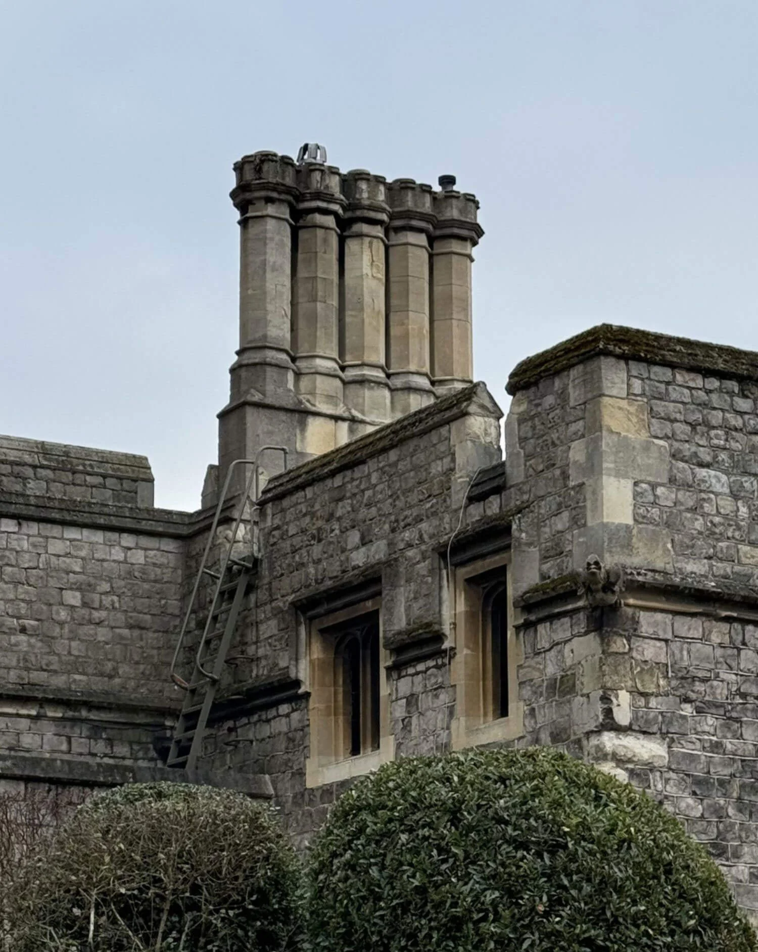 Clustered stone chimney shafts above a slate roof