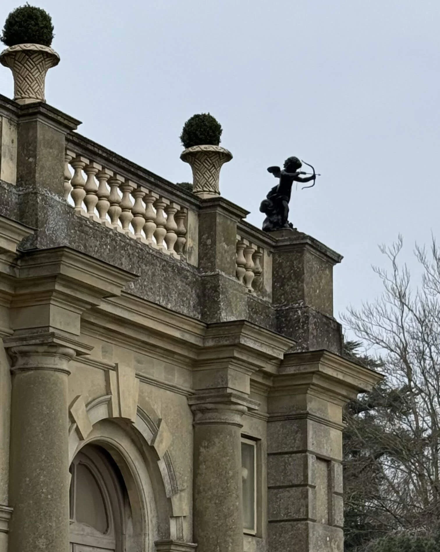 Stone balustrade and urns above an arched entrance