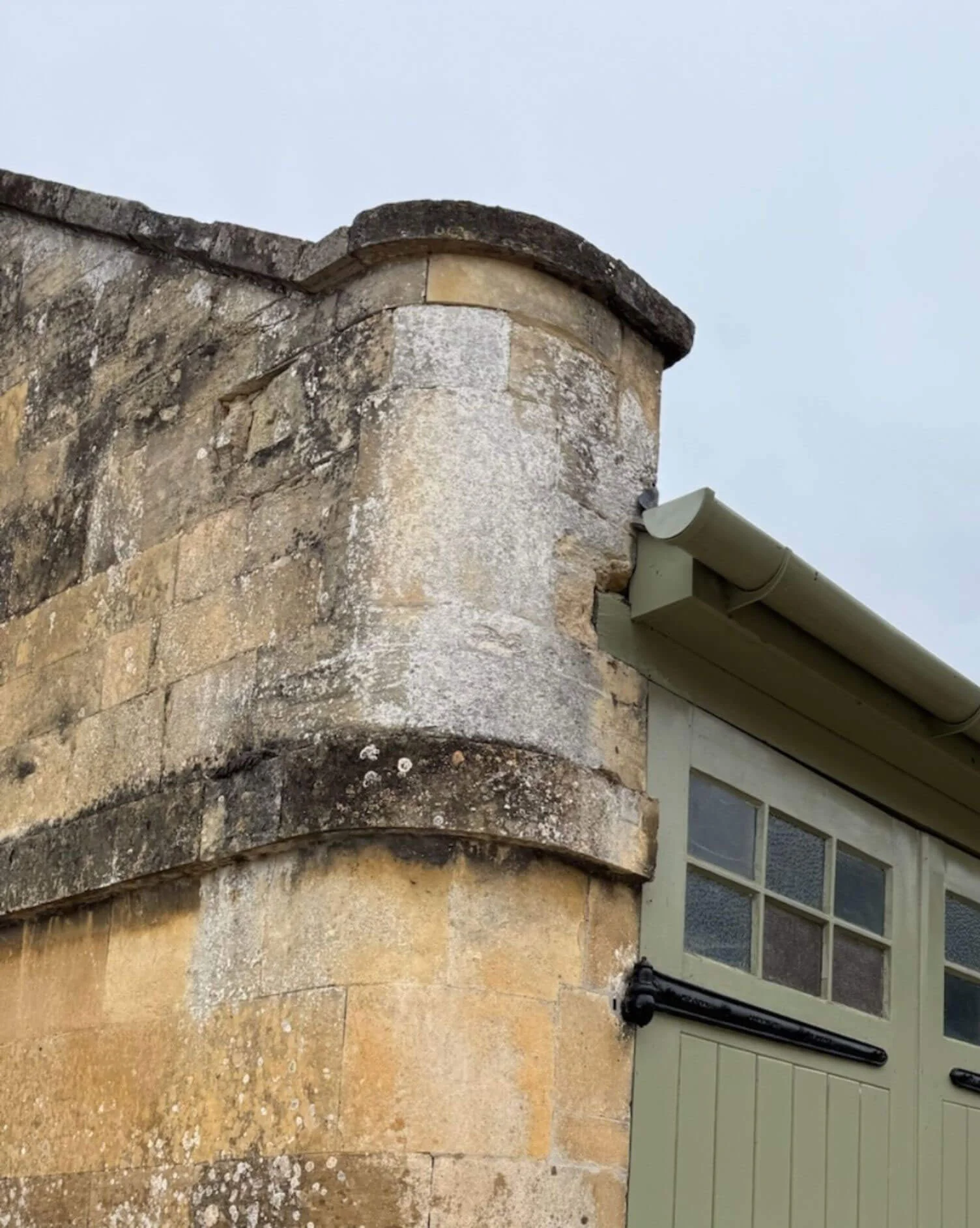 Curved weathered stone parapet above a window