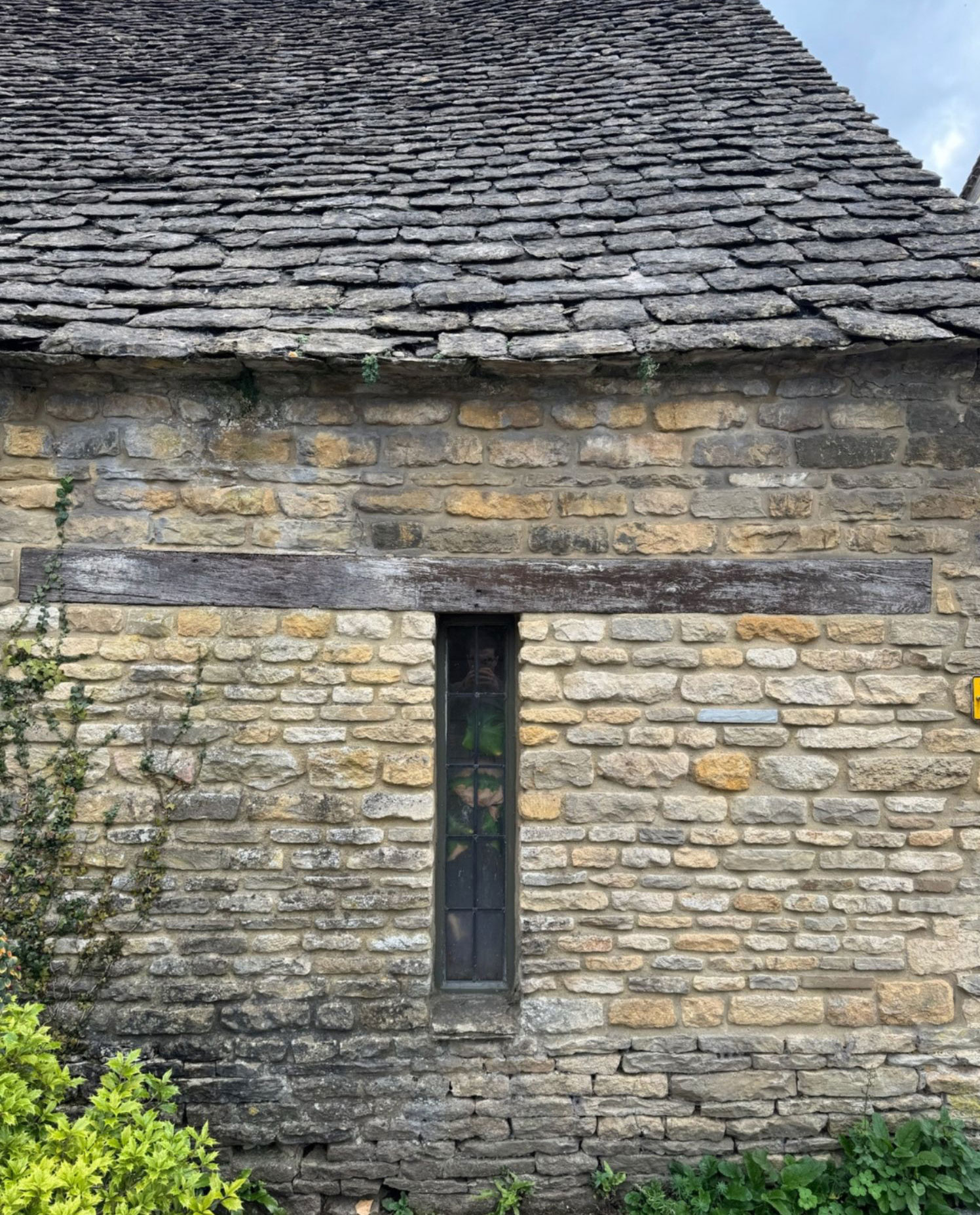 Narrow vertical window in a weathered stone facade
