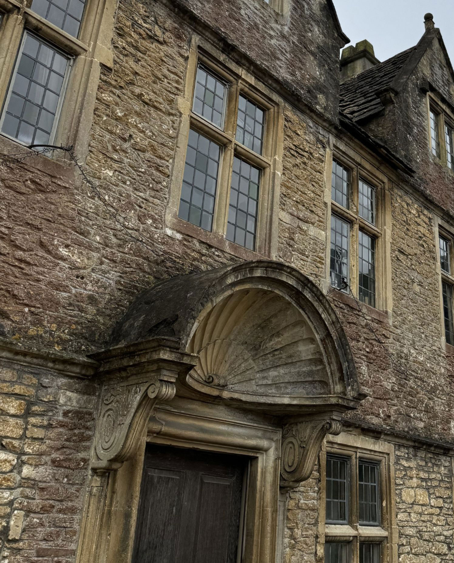 Arched stone door surround beneath mullioned windows