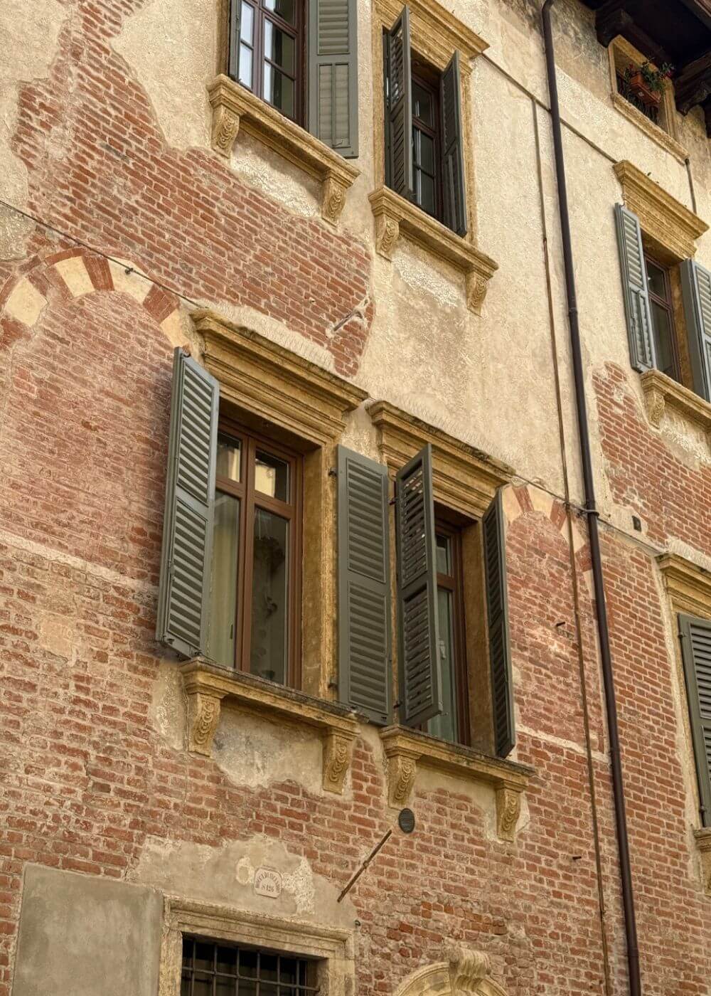 Weathered painted facade with shuttered windows