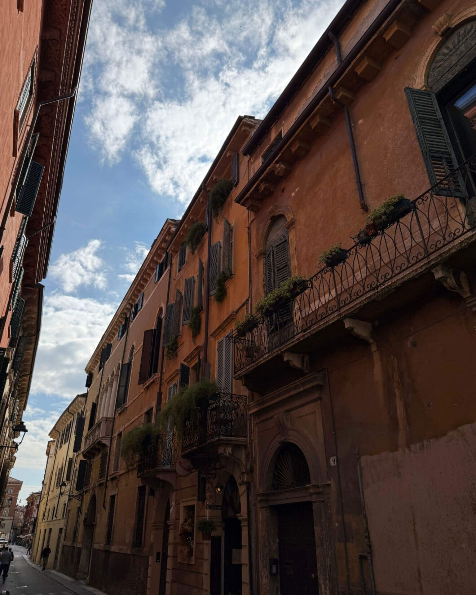 Warm brick facade with balconies above an arched doorway