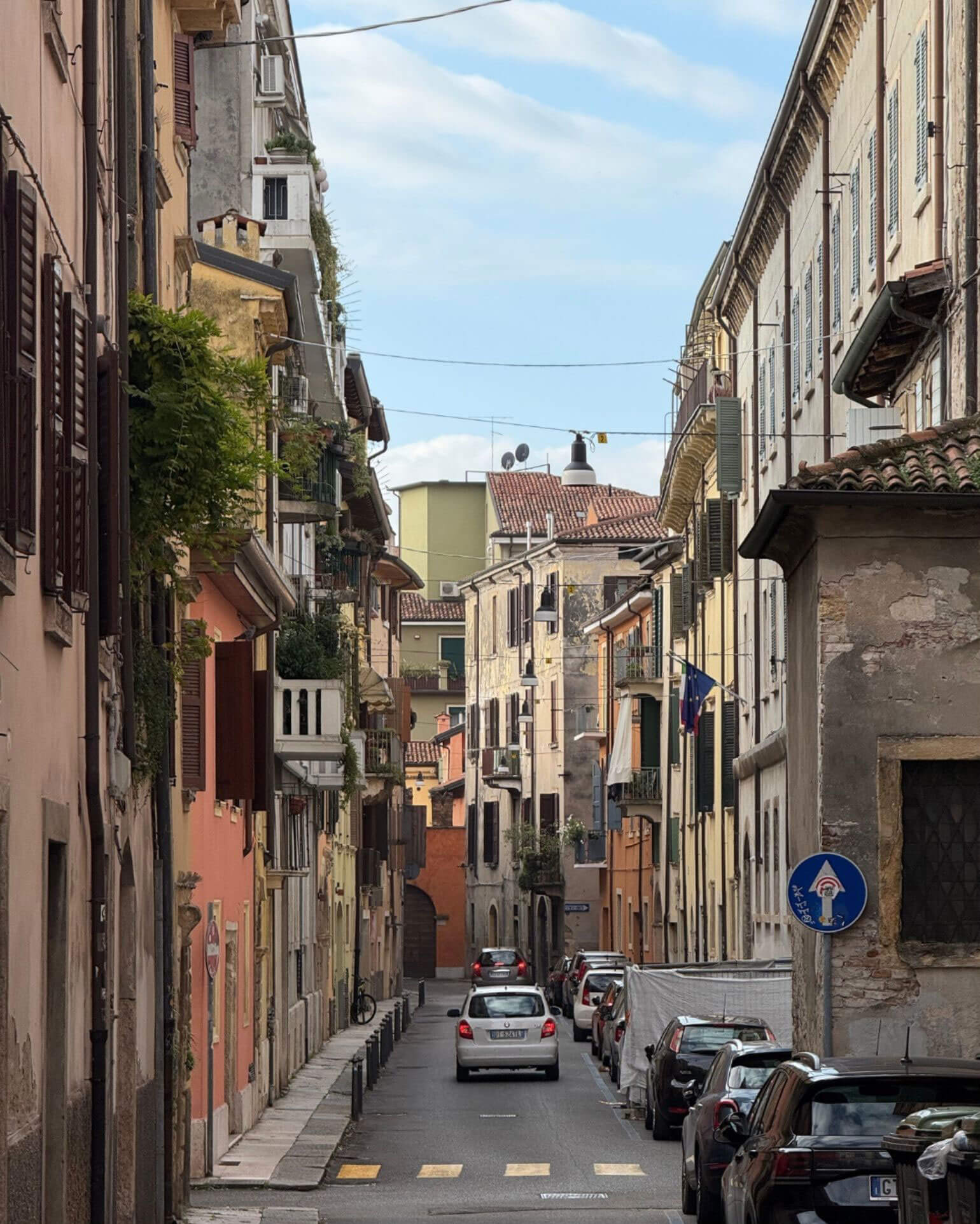 Narrow street framed by balconies and stone facades