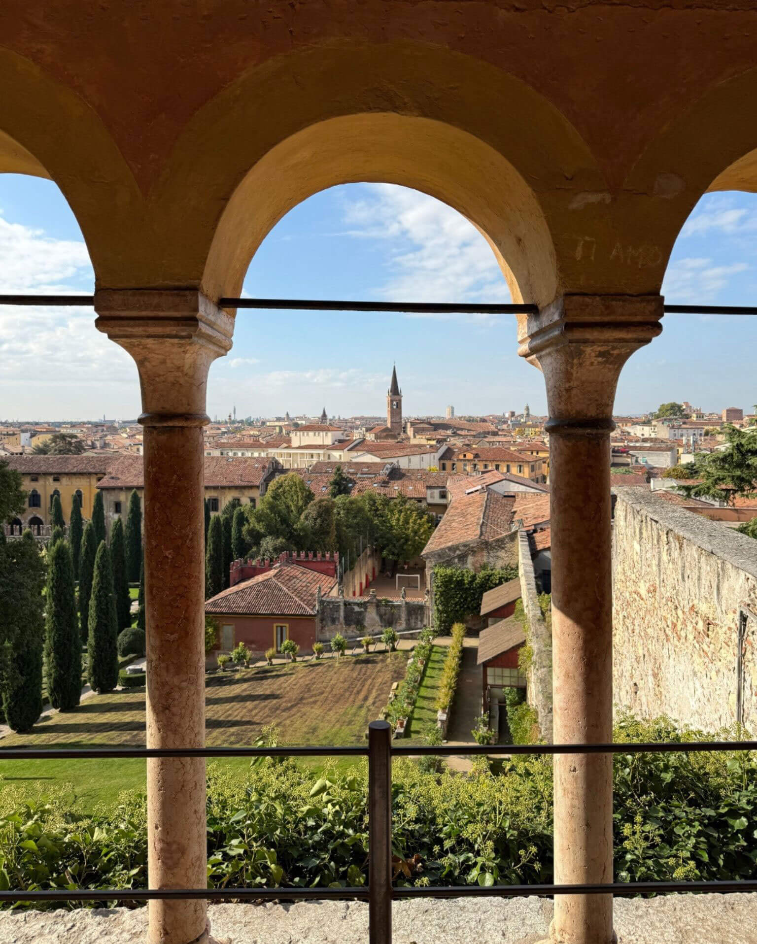 Formal garden and city view through a stone arcade