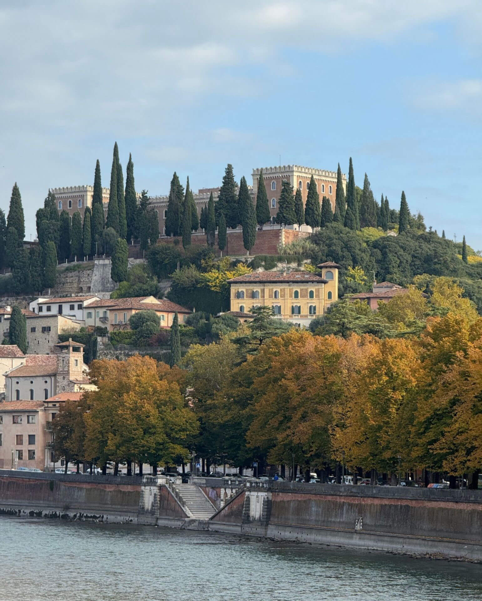Hilltop buildings above a tree-lined riverbank