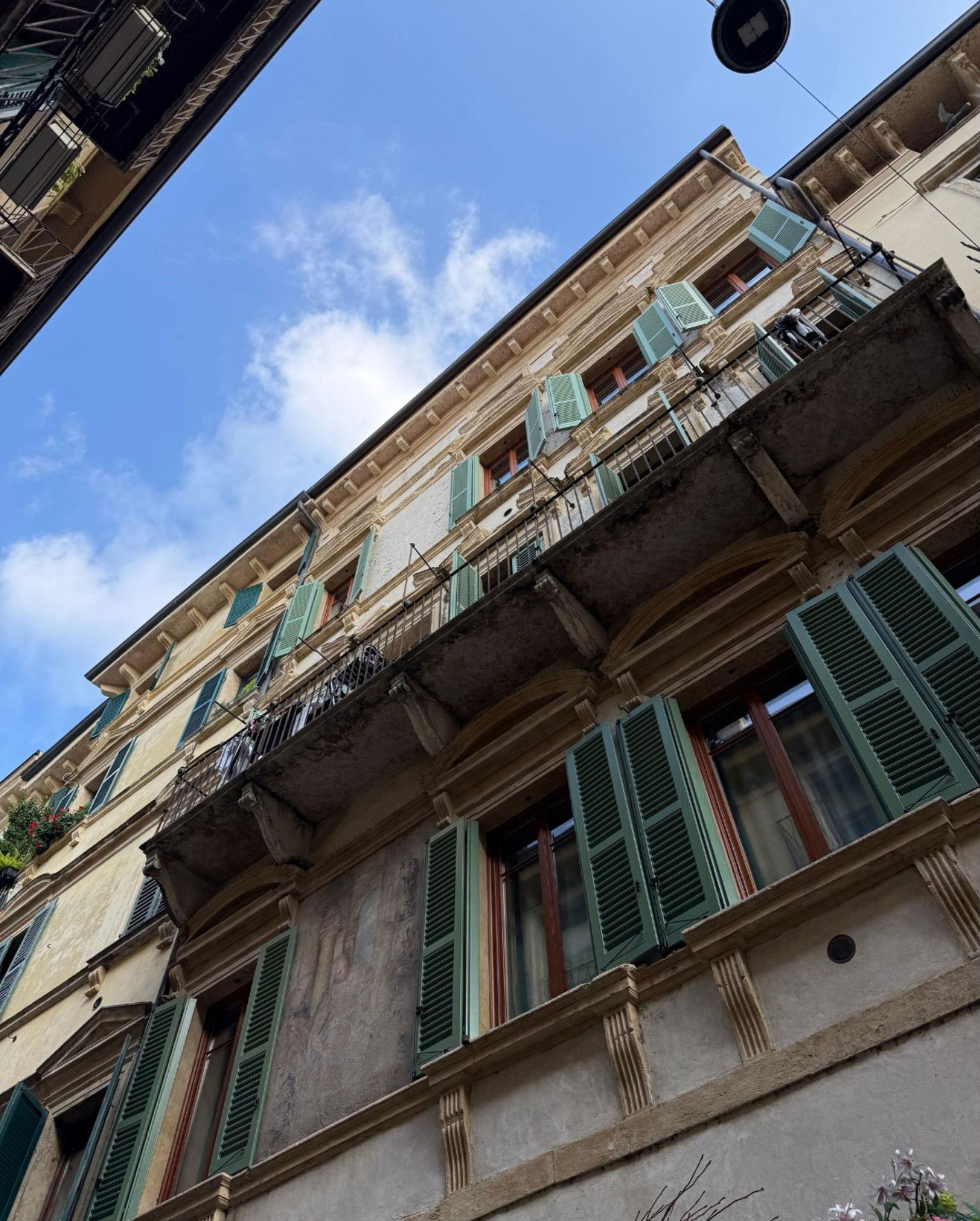 Stone balcony with green shutters viewed from below