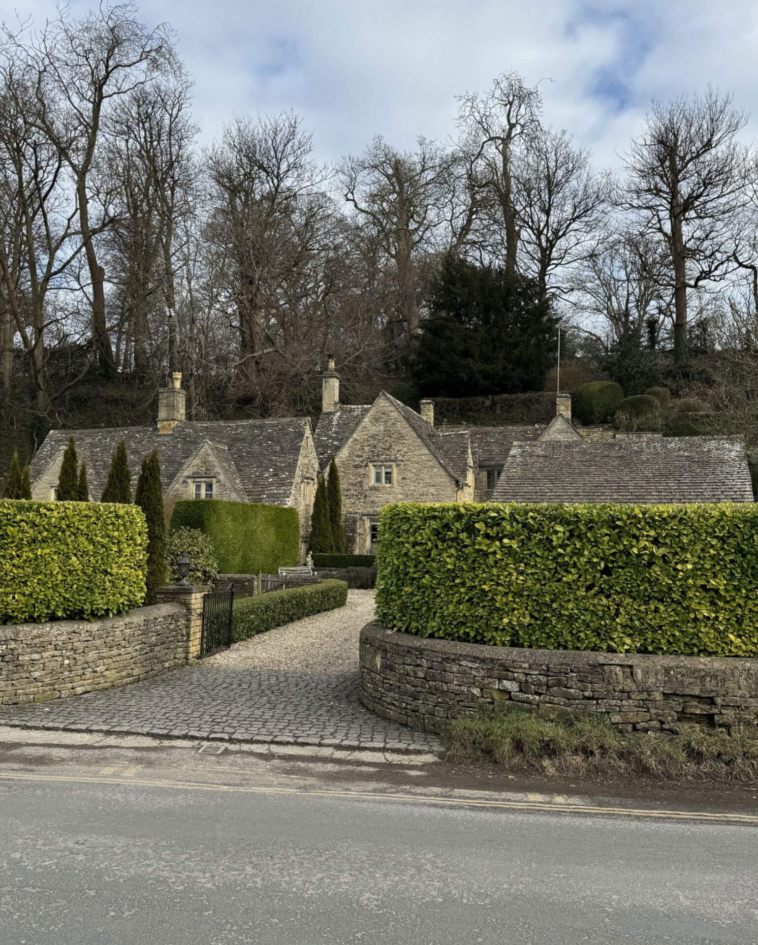 Stone cottages behind clipped hedges and a low garden wall