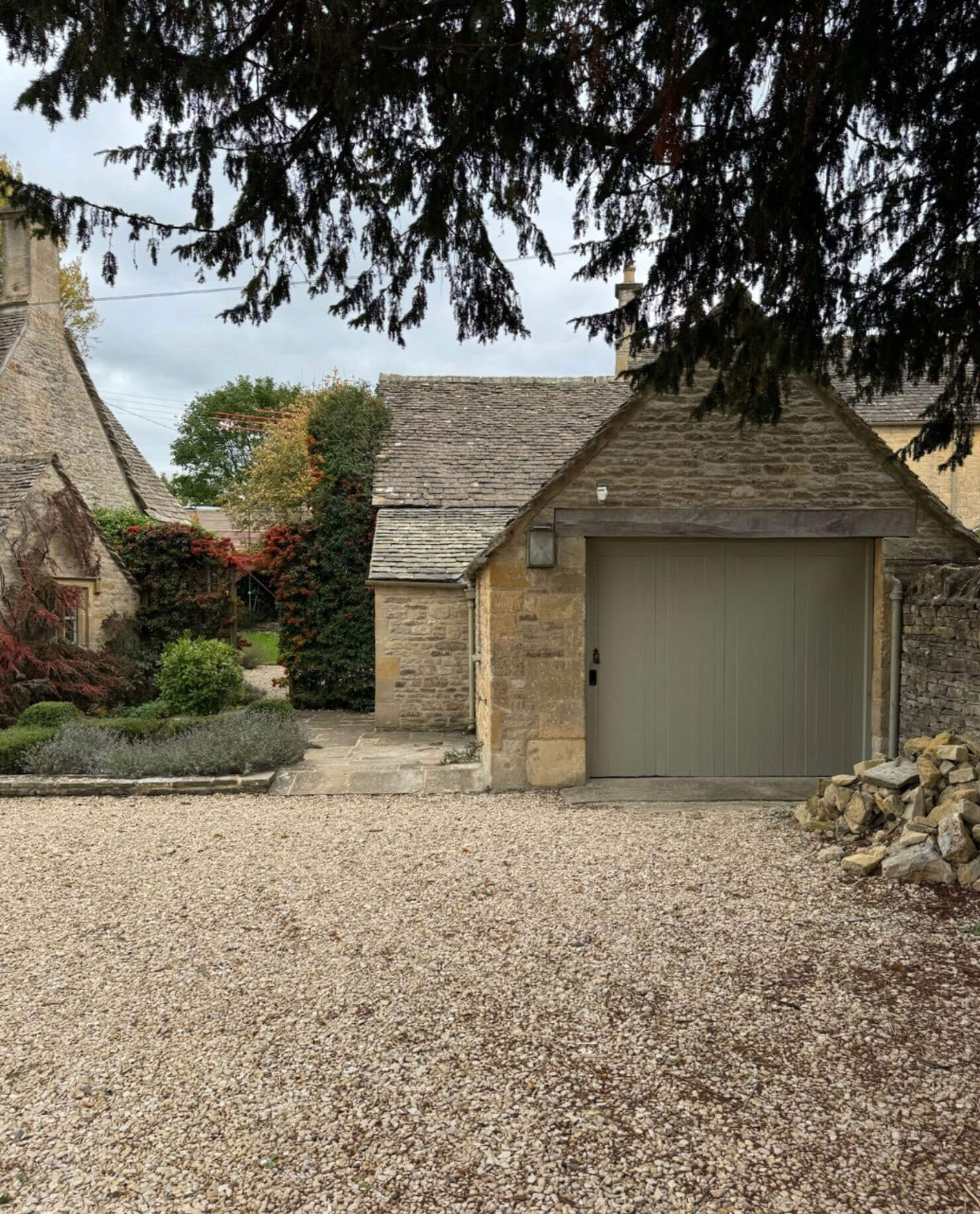 Stone garage and gravel courtyard beneath a tree