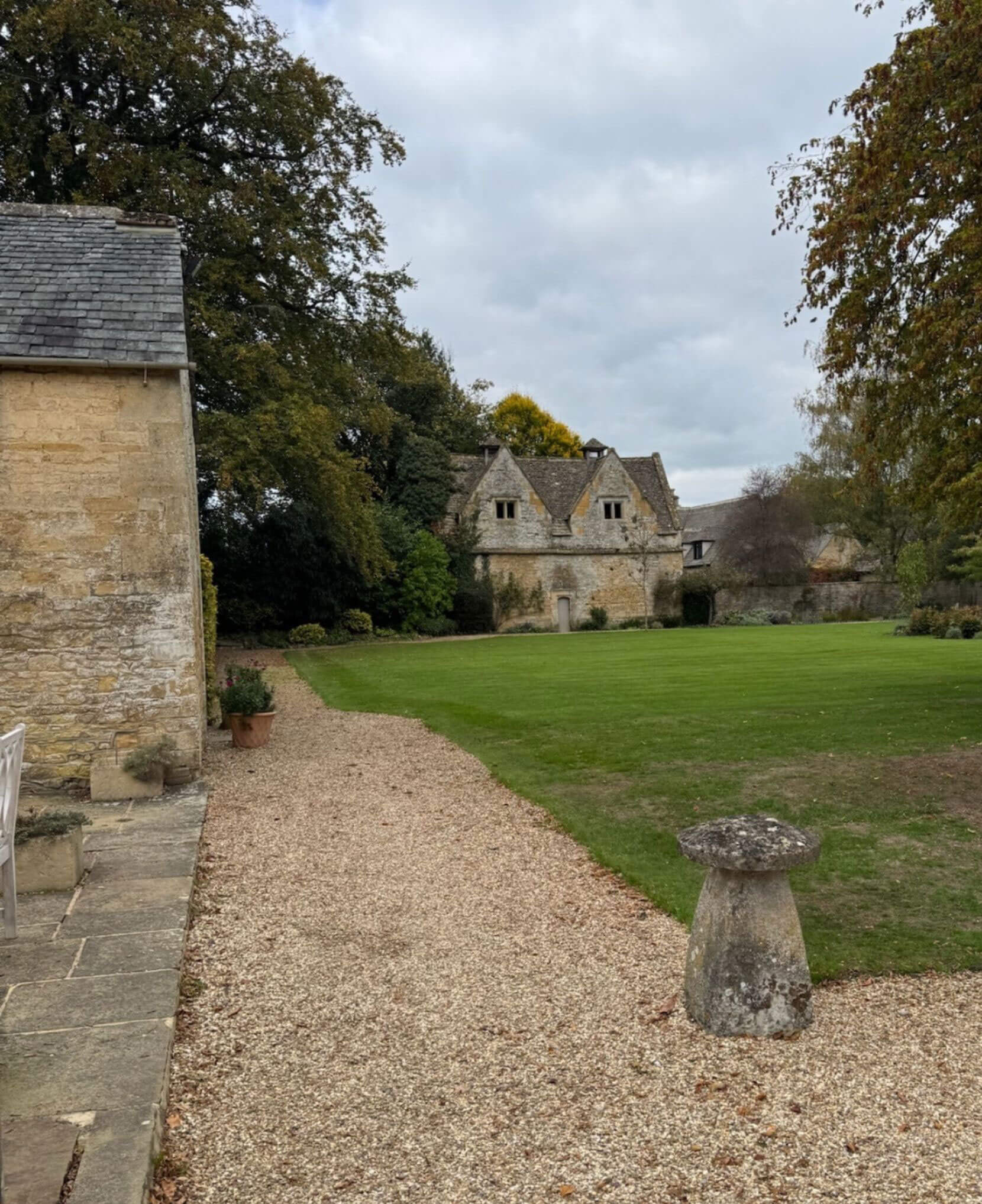Gravel path beside a stone house and garden ornament