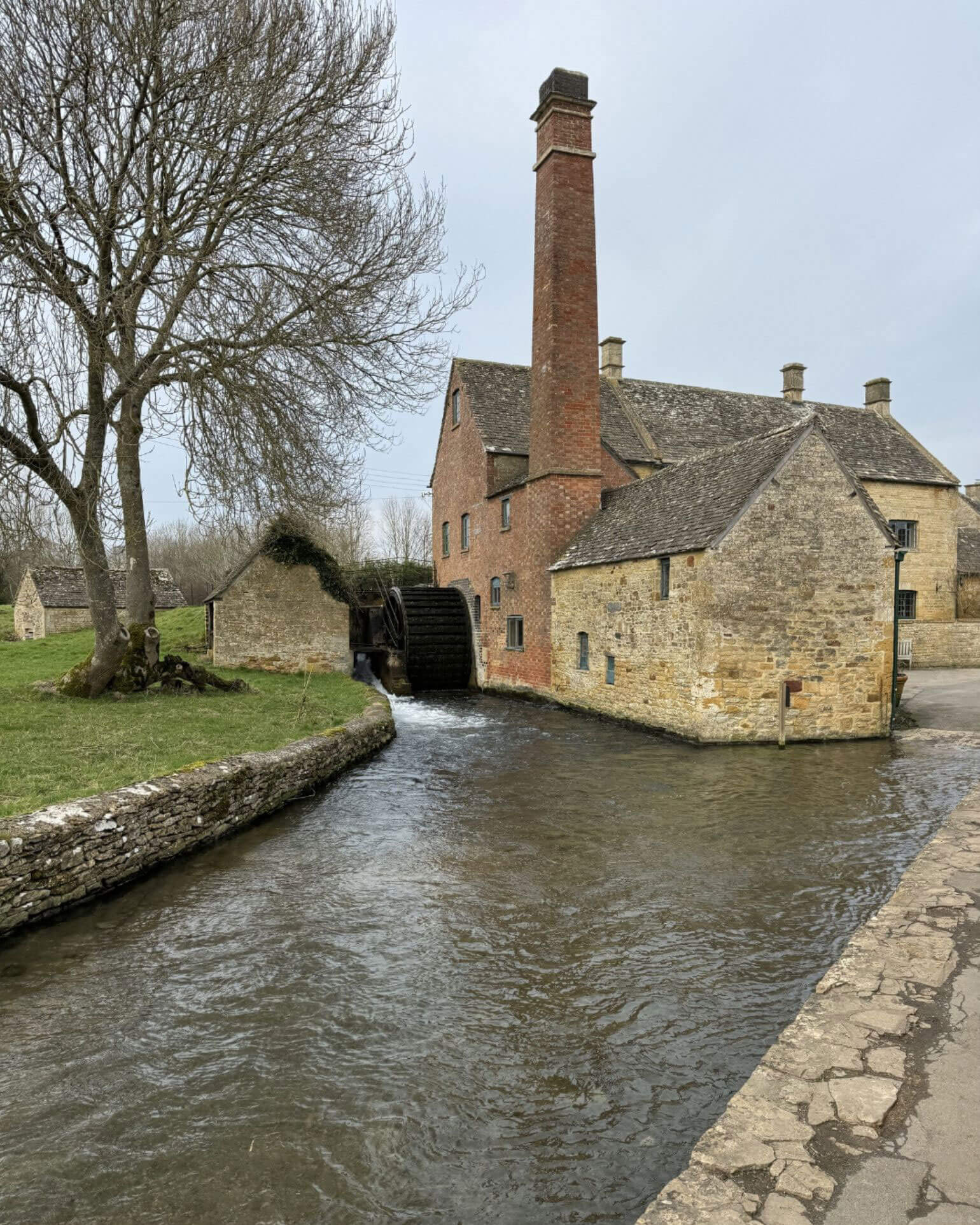 Riverside stone building with a tall brick chimney