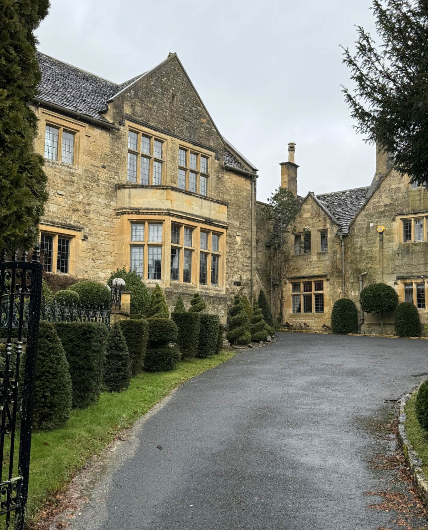Curving driveway beside a manor and clipped topiary