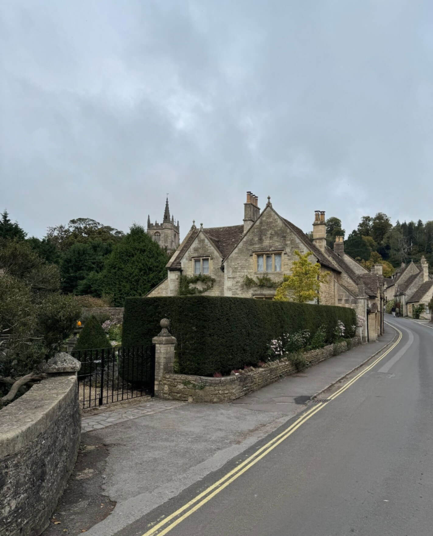Stone village house behind garden walls and hedges