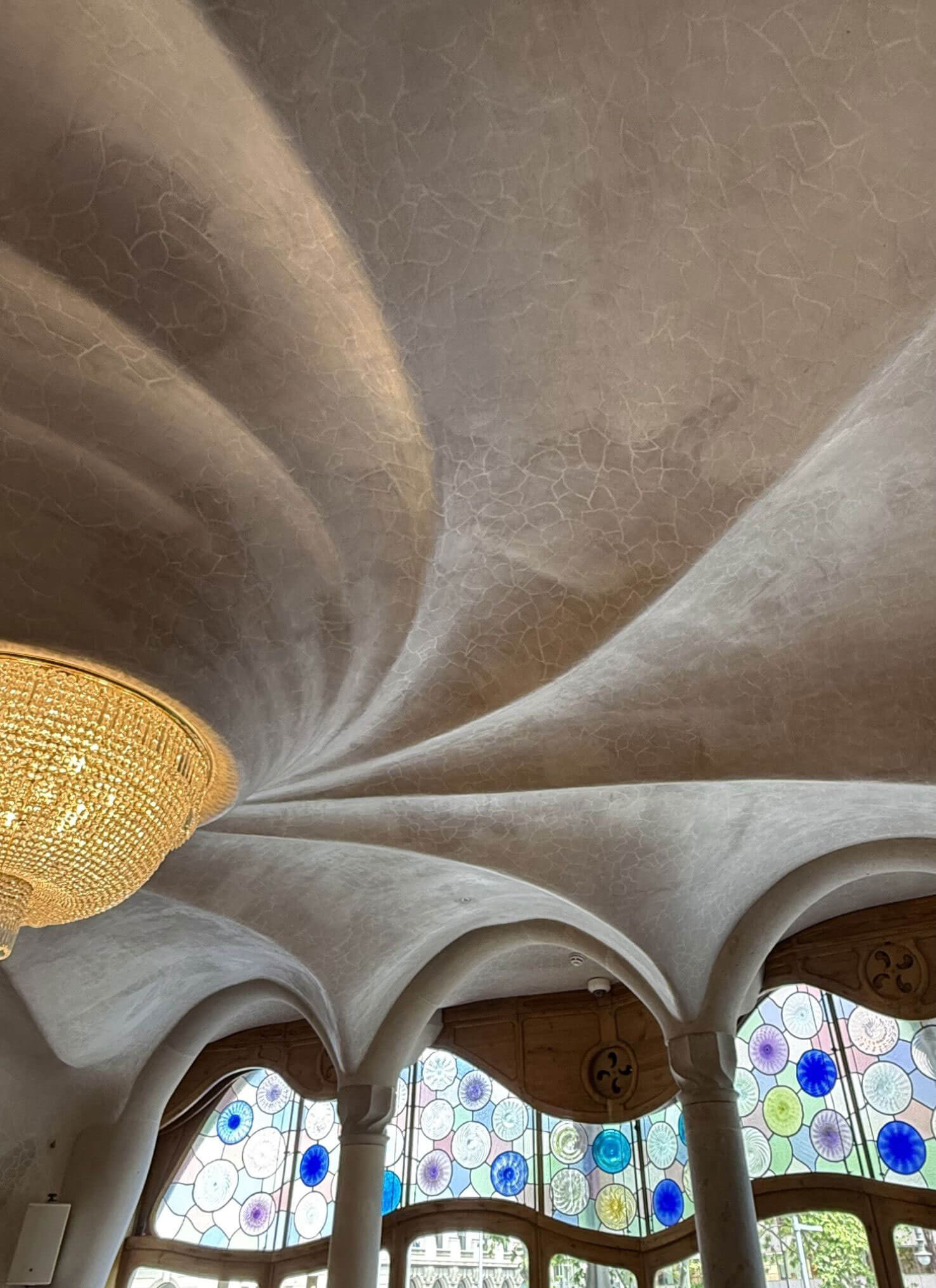 Spiral ceiling above a chandelier and curved windows
