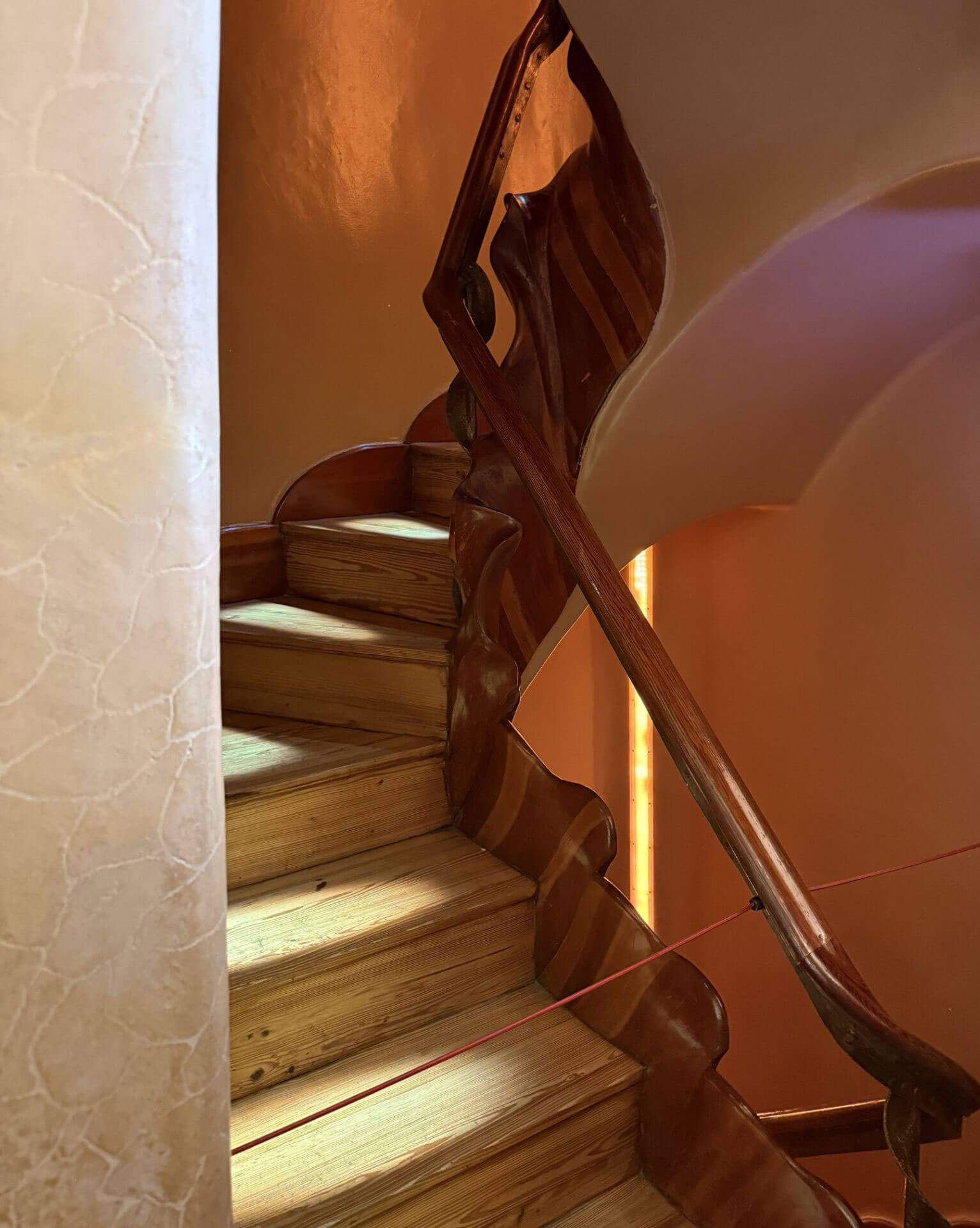 Curving wooden staircase and carved banister