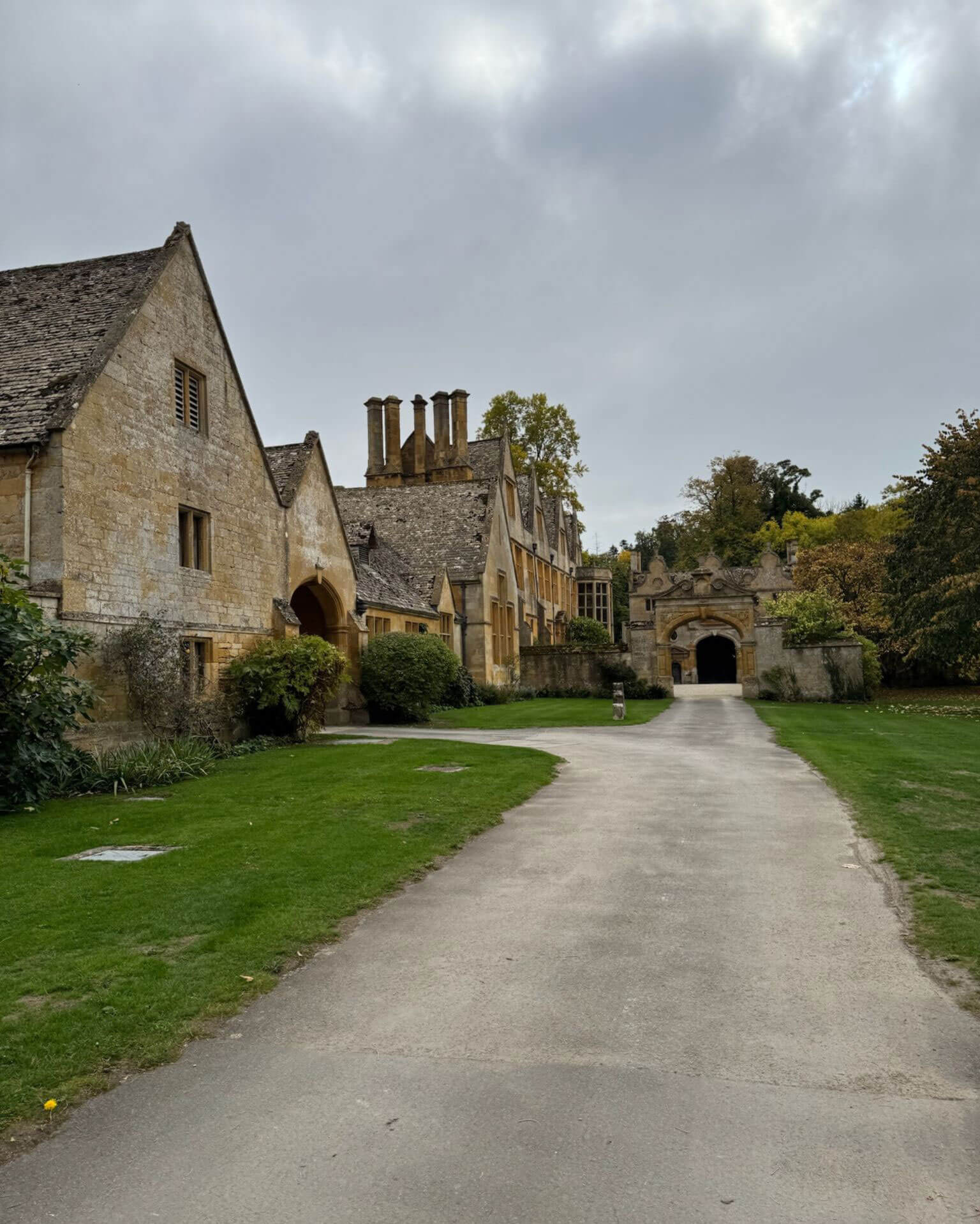 Gravel drive approaching the gabled stone buildings of Stanway House