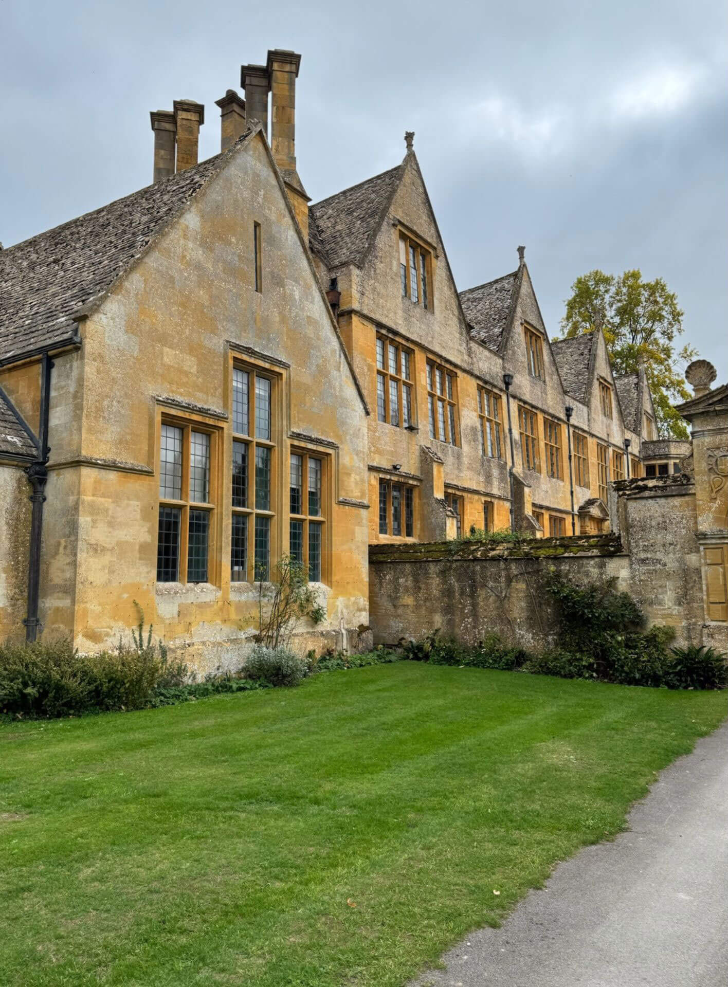 Gabled limestone facade beside a green lawn