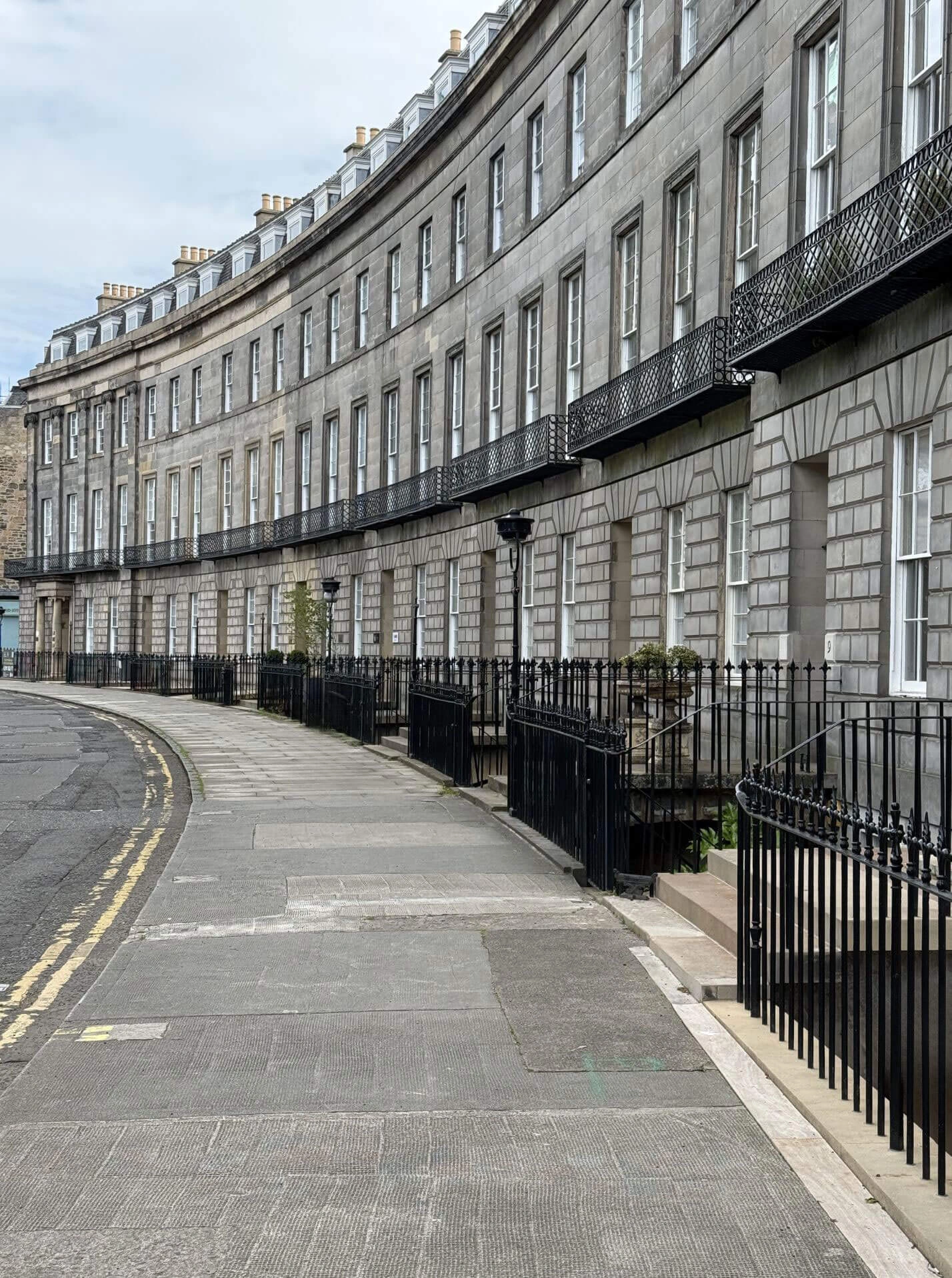 Curved terrace of stone townhouses with iron railings